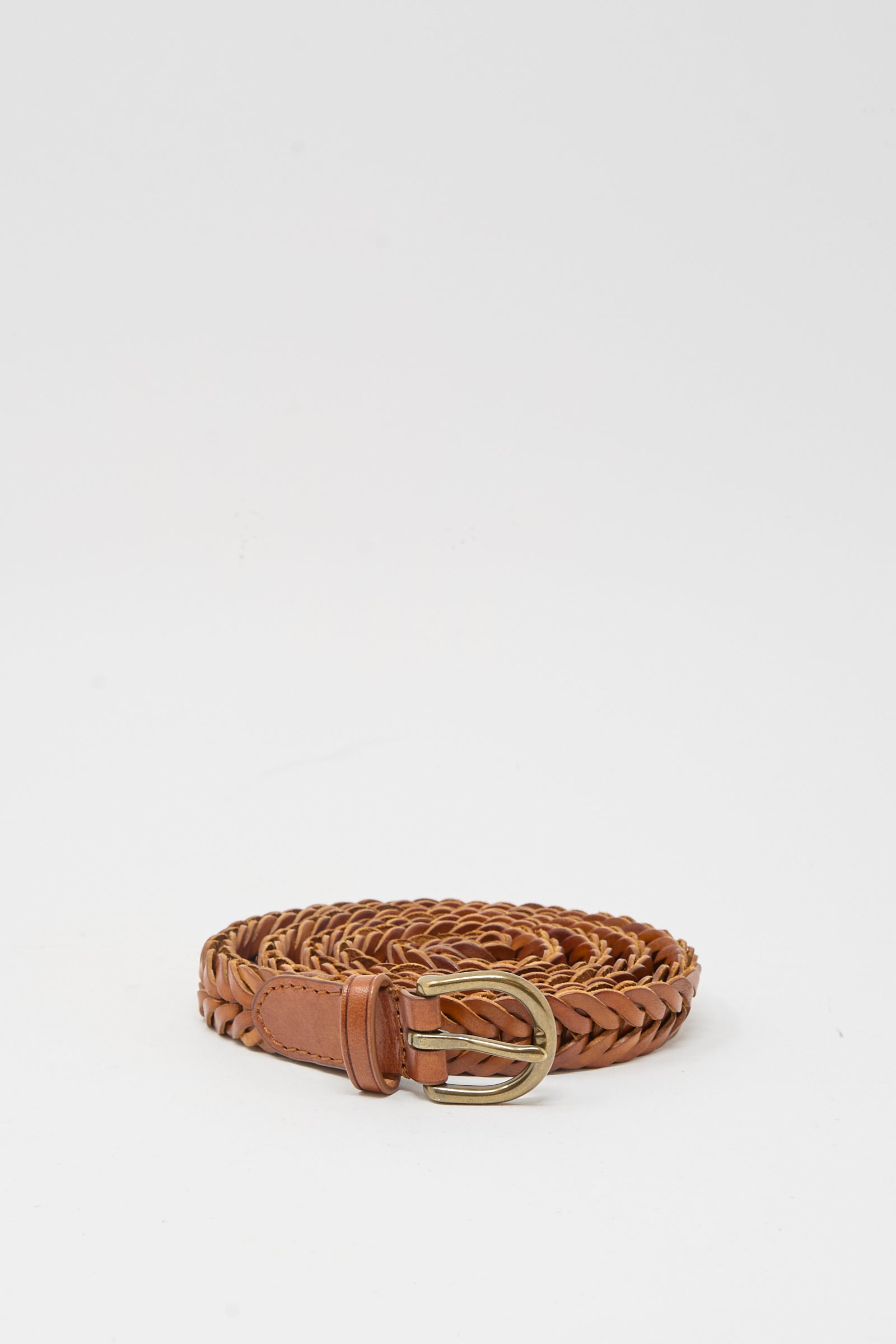 The Brass Buckle Single Link Belt in Tan by Dragon Diffusion, featuring a brass buckle and handcrafted braided leather, is displayed rolled up on a plain white background.