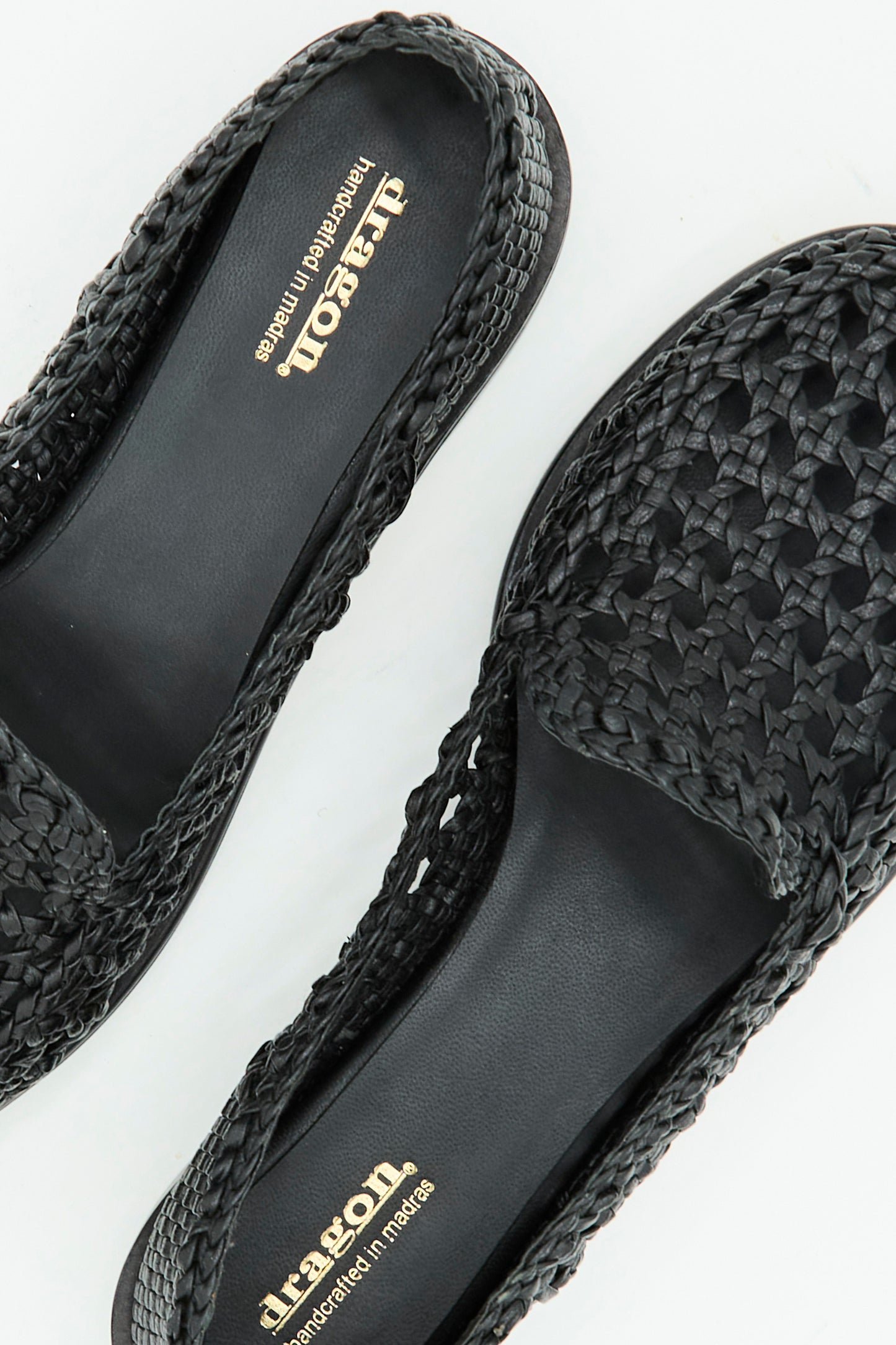 Close-up of the Dolly Moccasin in Black by Dragon Diffusion, featuring woven leather slip-on design and gold "Dragon" branding on the insole, displayed on a white surface.