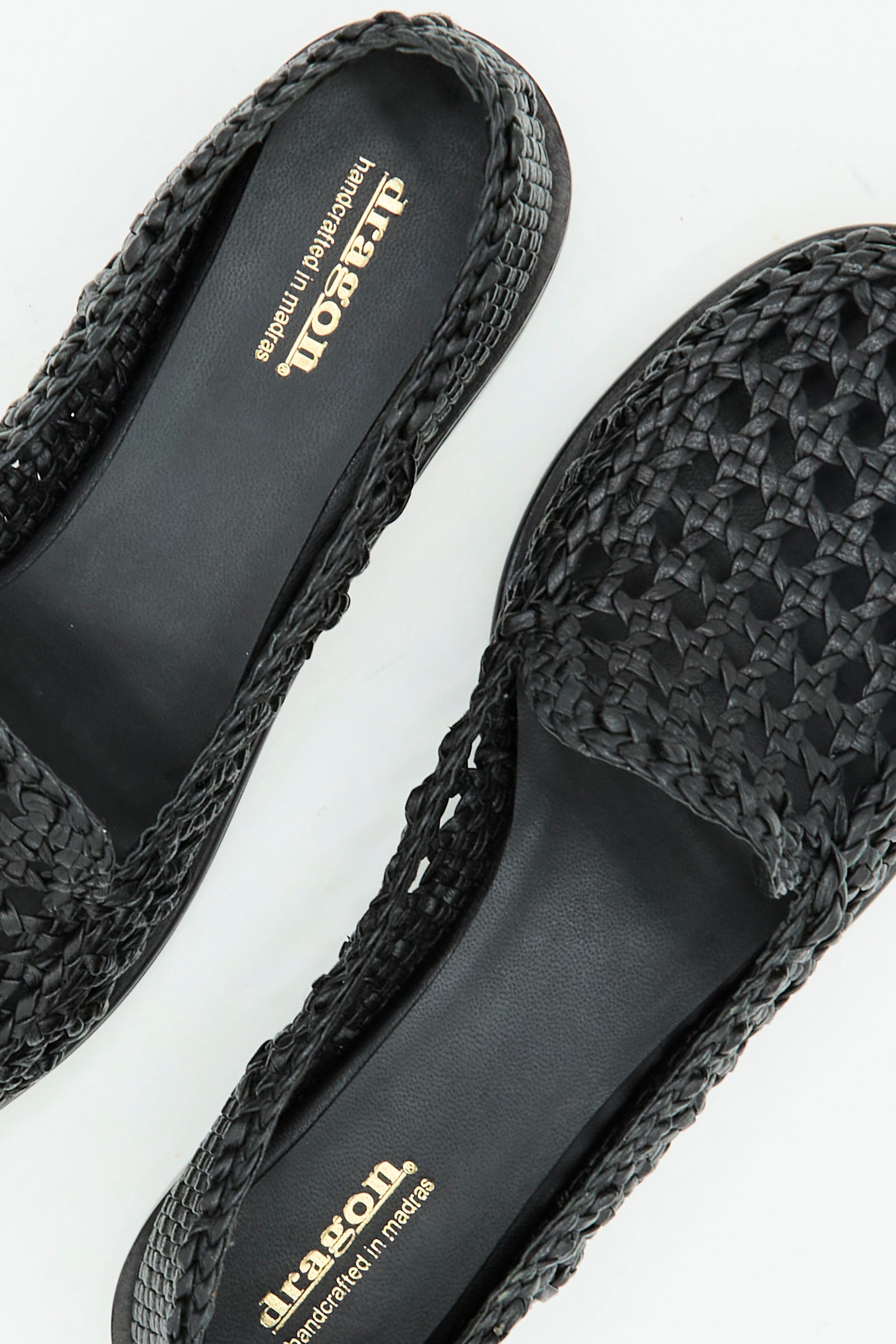 Close-up of the Dolly Moccasin in Black by Dragon Diffusion, featuring woven leather slip-on design and gold "Dragon" branding on the insole, displayed on a white surface.