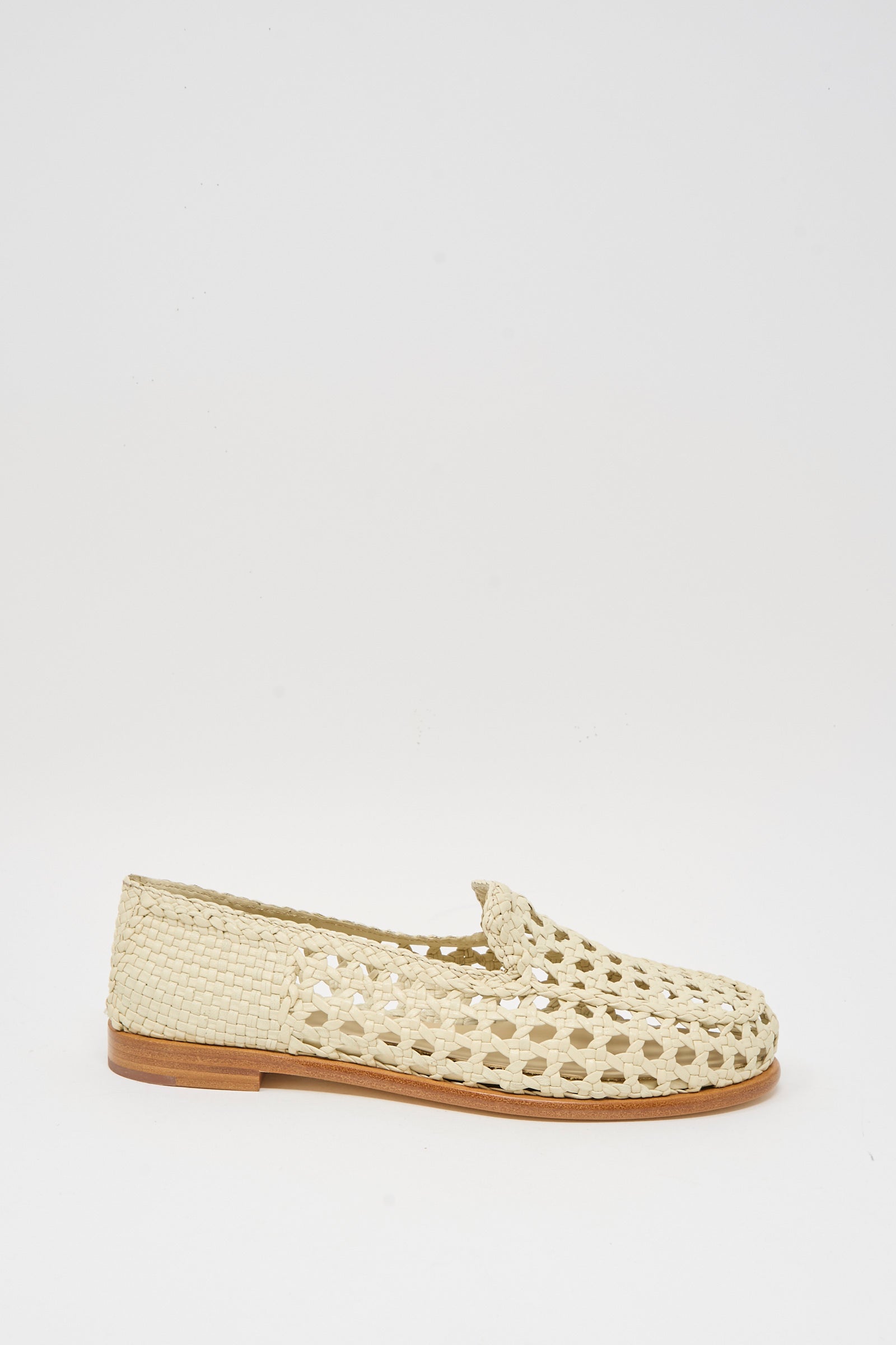 The Dolly Moccasin in Off White by Dragon Diffusion is a woven goat leather shoe with a closed toe, open-weave design, and flat wooden sole, shown against a plain white background.