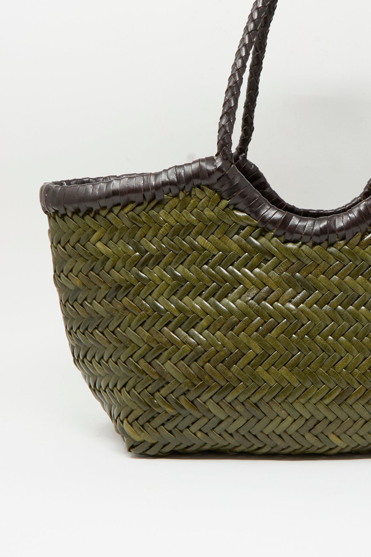 A close-up of the Dragon Diffusion Nantucket Small Bi-Color bag in dark brown and khaki, crafted from handwoven calf leather in a basket shape with dark brown woven handles and trim, displayed against a plain white background.