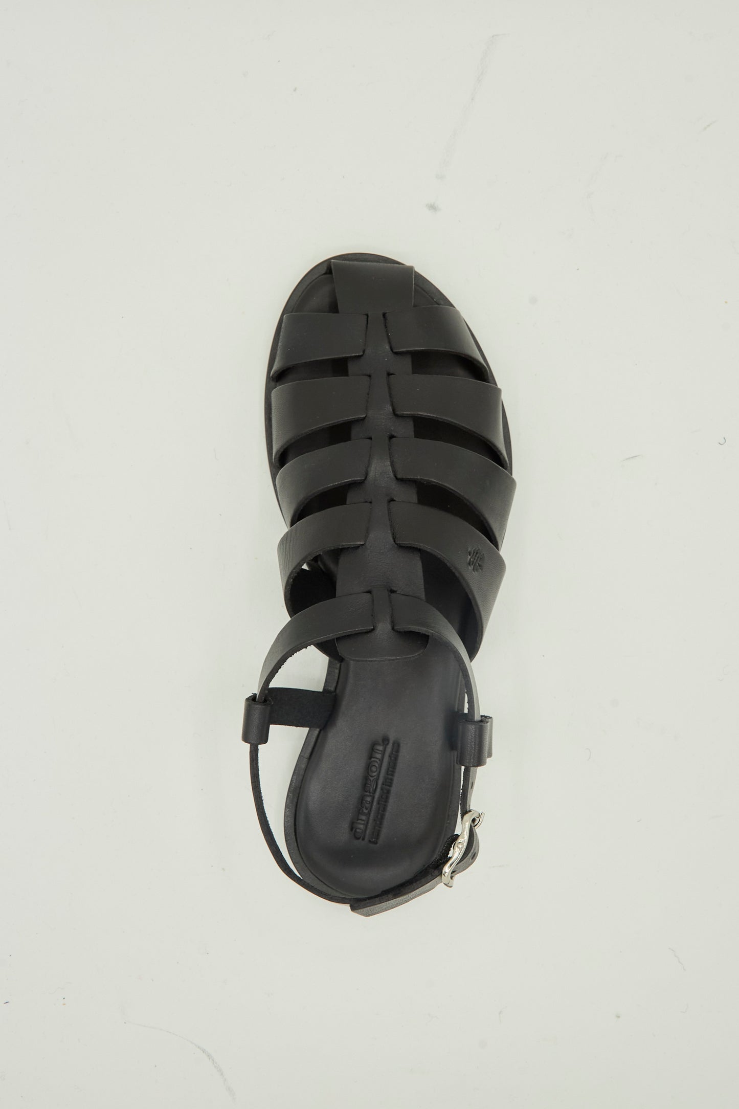 The Pescador Sandal in Black by Dragon Diffusion is a handcrafted, premium cow leather fisherman sandal featuring a closed toe and ankle strap, shown from above on a plain light background.