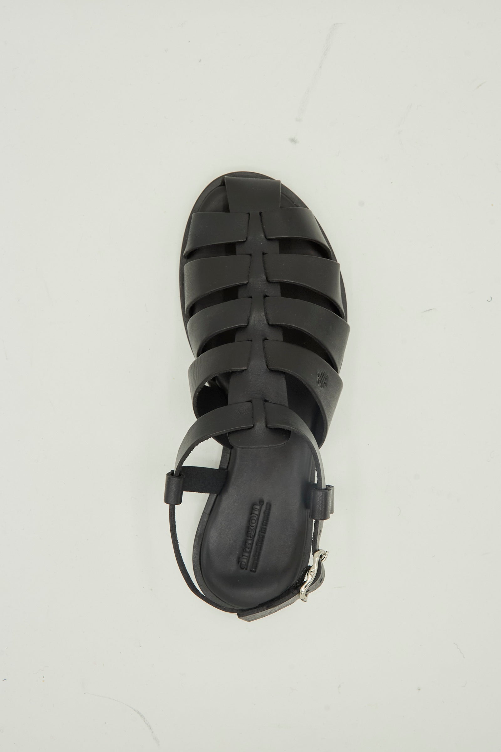 The Pescador Sandal in Black by Dragon Diffusion is a handcrafted, premium cow leather fisherman sandal featuring a closed toe and ankle strap, shown from above on a plain light background.