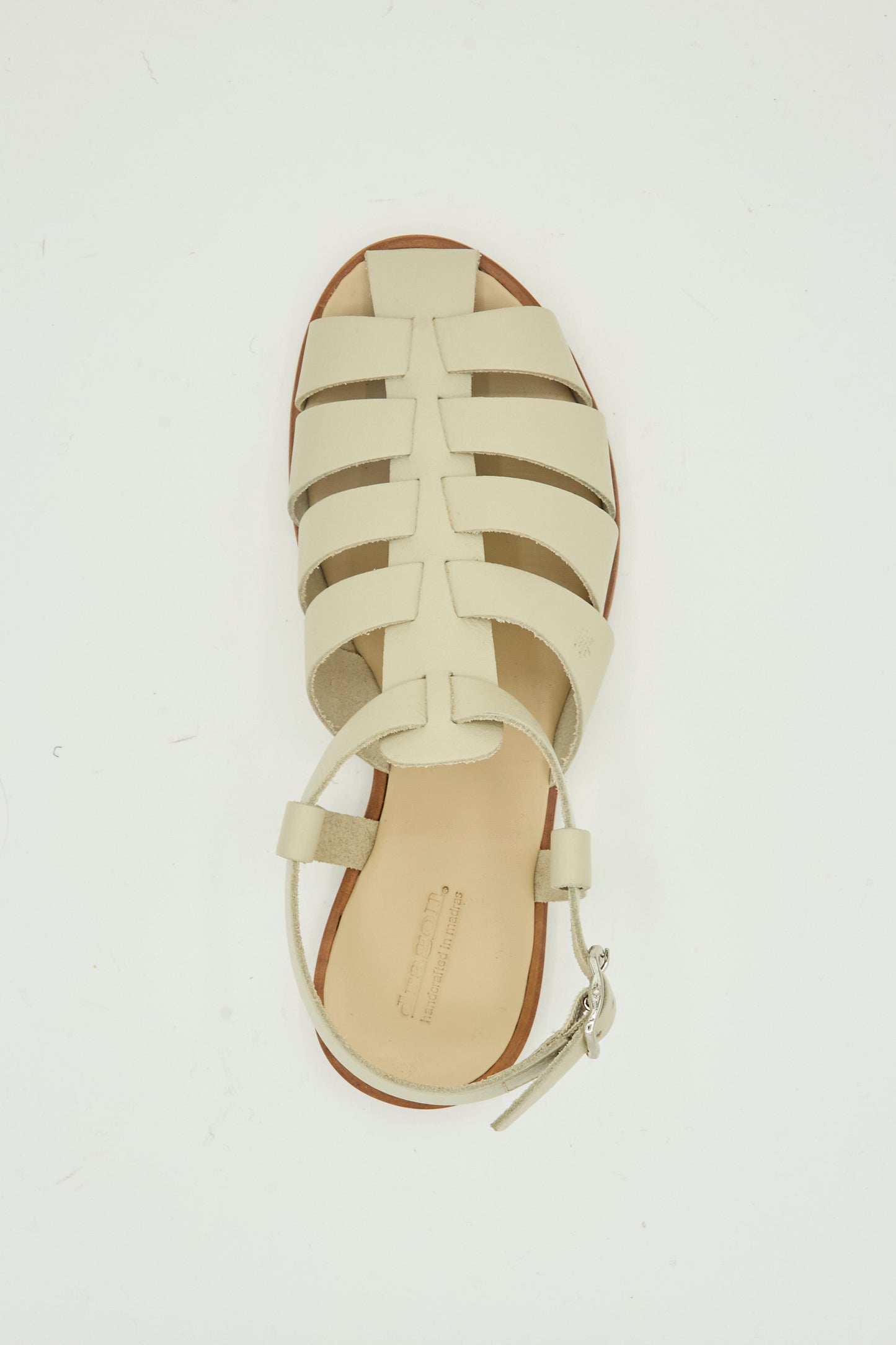 The Dragon Diffusion Pescador Sandal in Pearl is a handcrafted beige cow leather fisherman style with a closed toe, cutout design, and ankle strap buckle, shown from above on a white background.