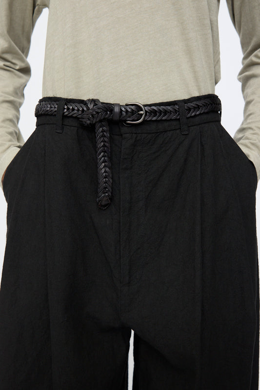 Wearing the Dragon Diffusion Single Link Belt in Black, featuring a handcrafted braided leather design with a silver buckle, paired with black pants and a light gray long-sleeve shirt, hands in pockets.