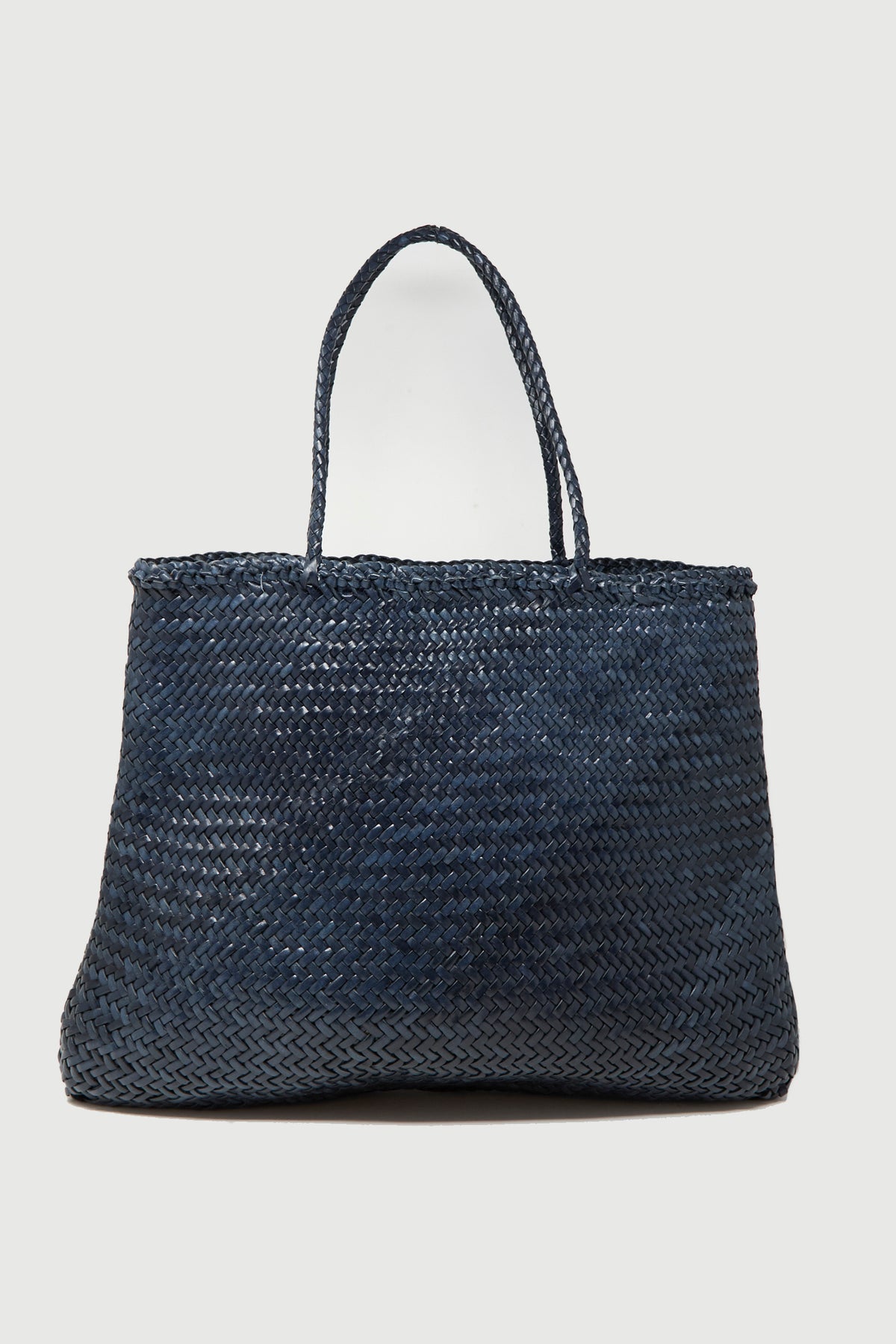 The Sophie Large in Marine by Dragon Diffusion is a spacious handwoven calf leather tote bag in navy blue, featuring two handles and shown against a plain white background.