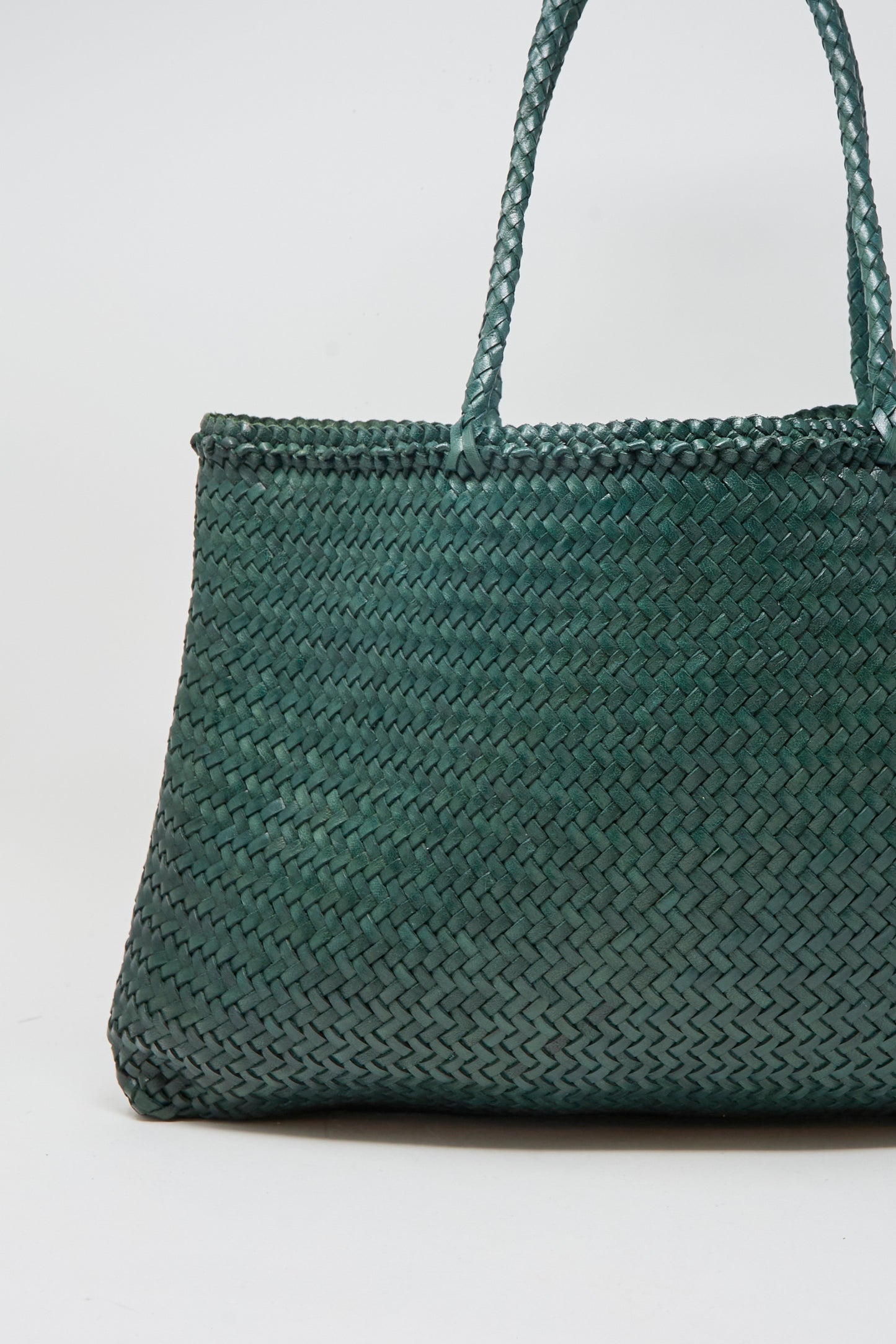 A close-up of the Dragon Diffusion Sophie Large tote in Forest, a dark green handwoven bag with two handles, set against a plain white background.
