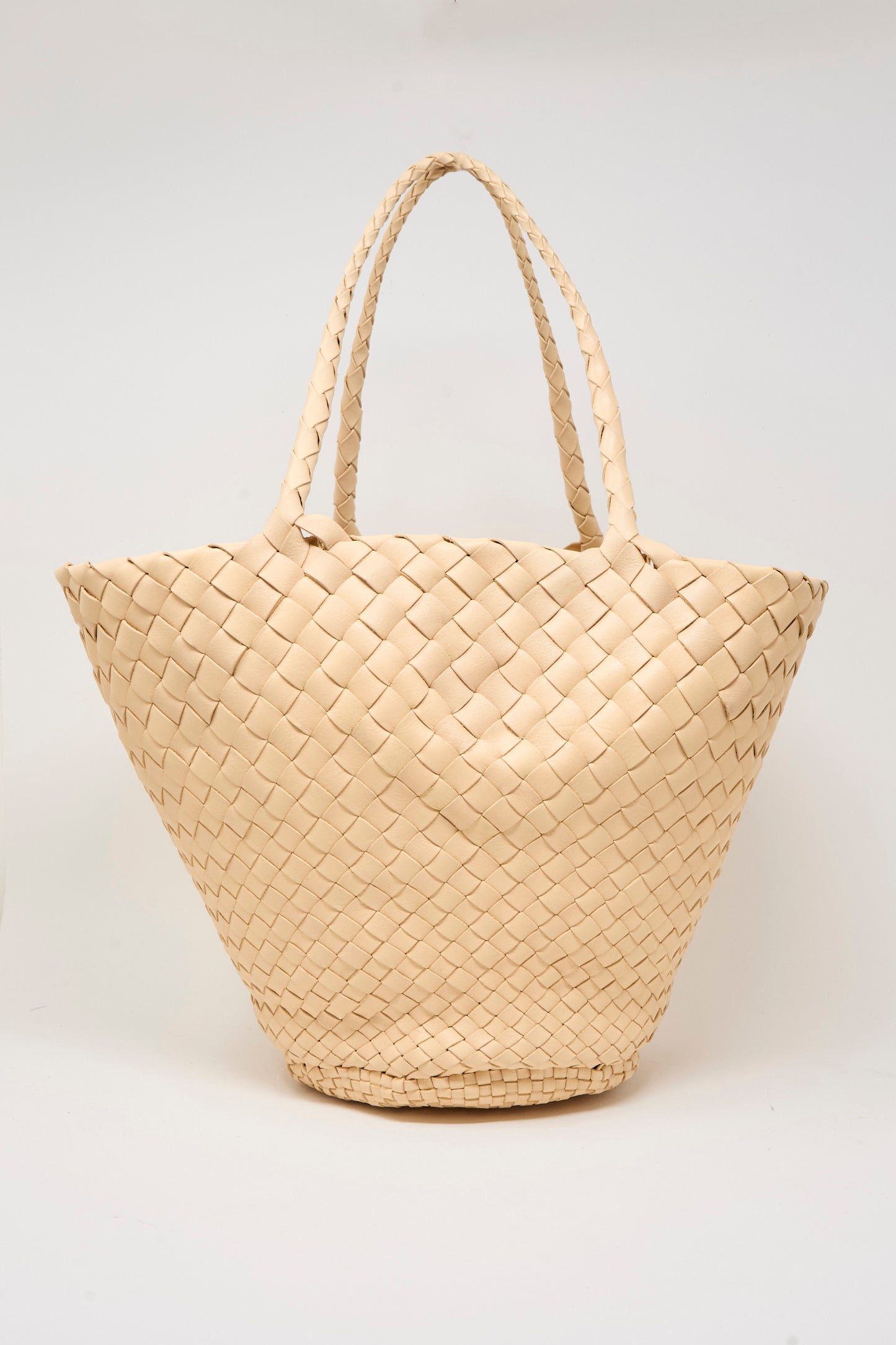The Egola in Natural by Dragon Diffusion is a large beige woven leather handbag with two handles, handmade in India and shown against a plain white background.