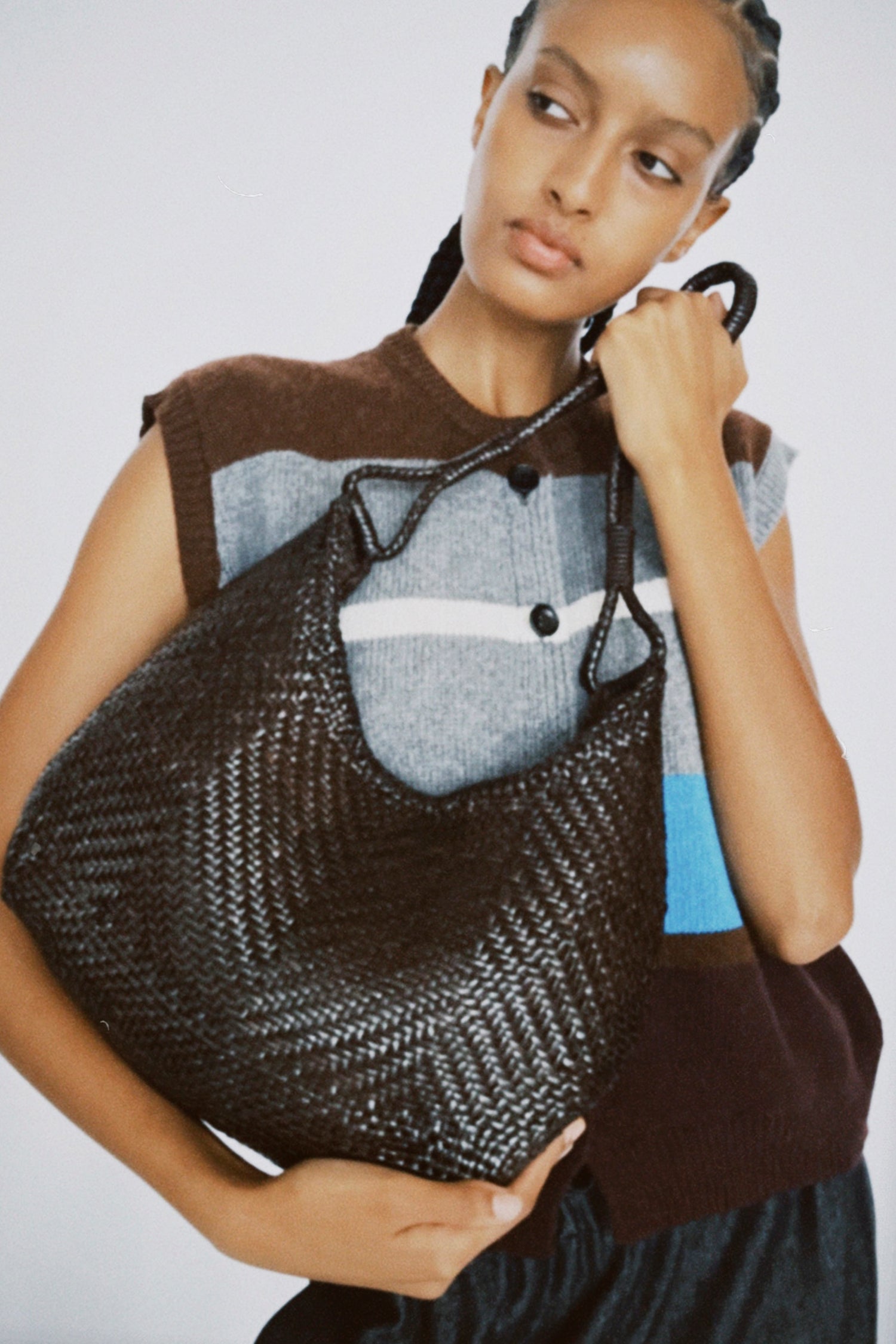 Woman holding the Dragon Diffusion Minga Hobo bag in Dark Brown against a plain background.