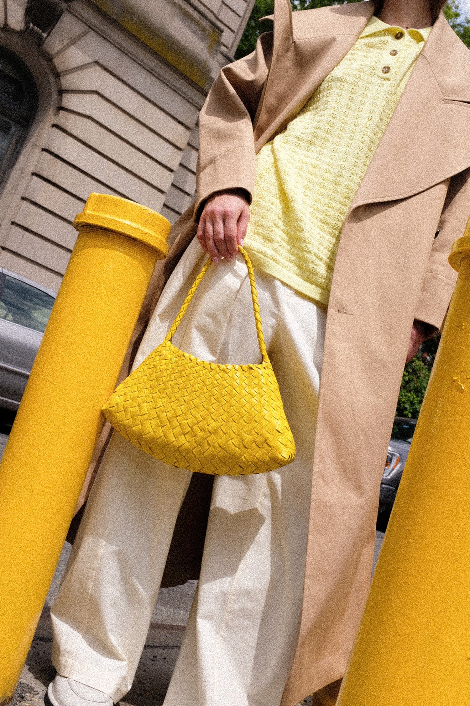 Person holding the Dragon Diffusion Rosanna Bag in Yellow with a cityscape background