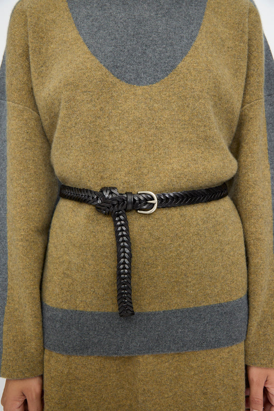 A person wearing a color-blocked sweater dress in olive and gray, cinched at the waist with the Dragon Diffusion Single Link Belt in Black, tied at the front.
