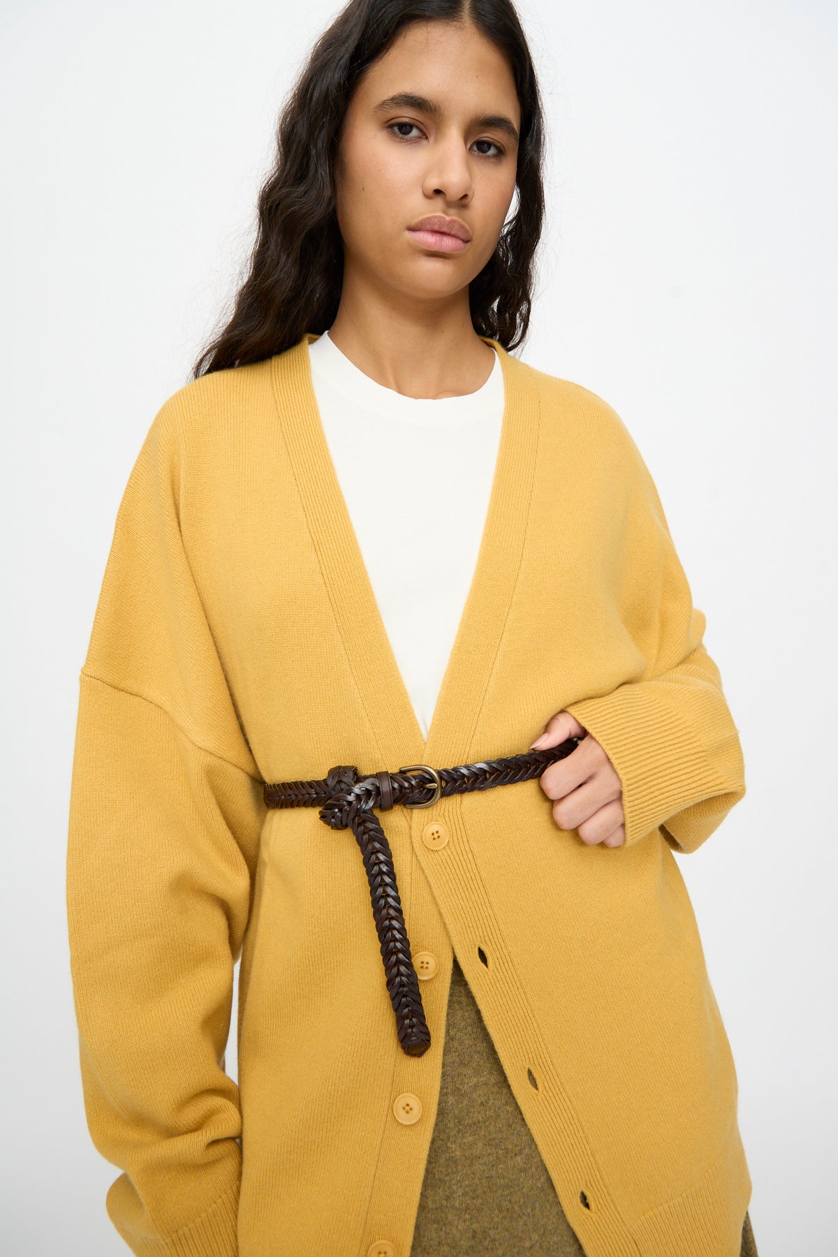 A person wearing a yellow cardigan over a white shirt, styled with the Dragon Diffusion Single Link Belt in Brown tied around the cardigan, stands against a plain background.