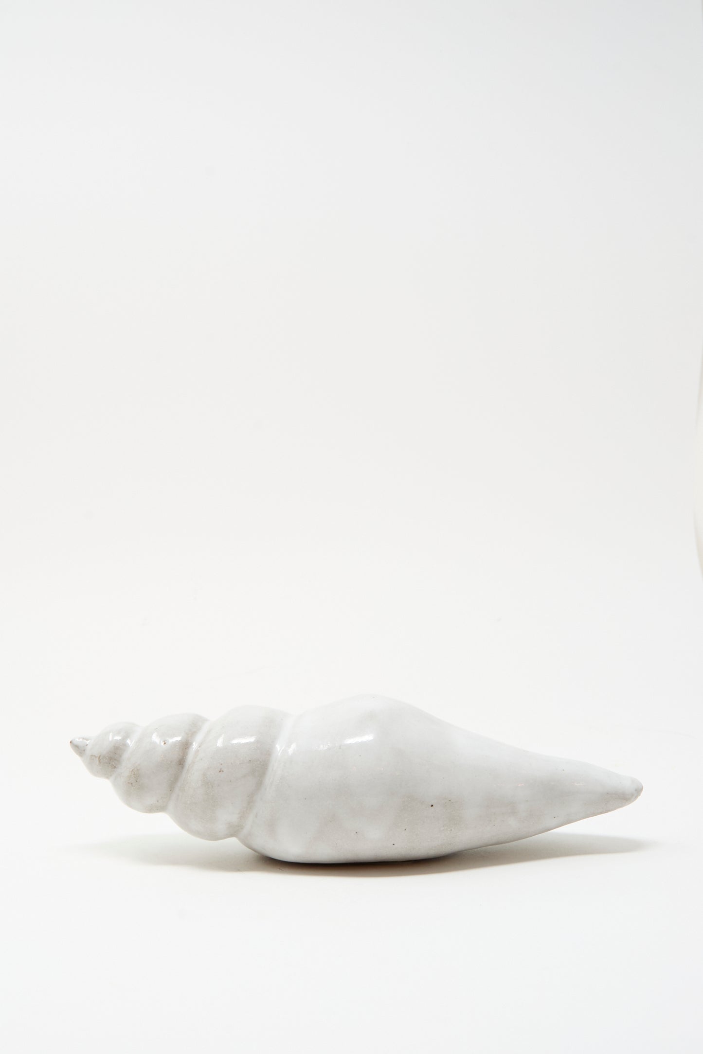 The Shell Rattle LXXXII by E.C.C.E, a handmade white ceramic piece crafted in NYC, is displayed against a plain white background.