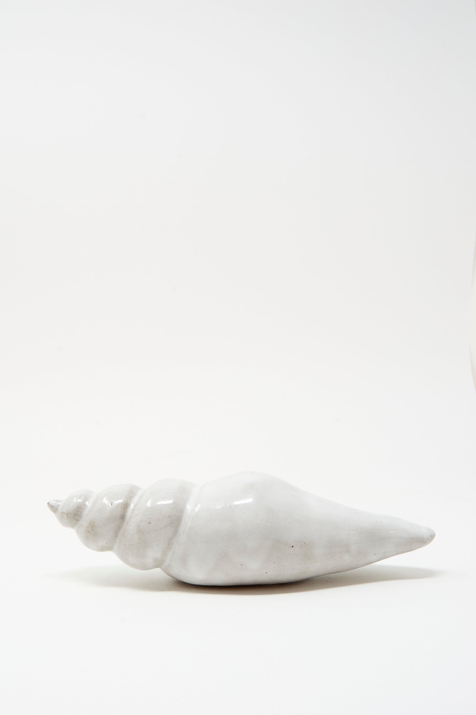 The Shell Rattle LXXXII by E.C.C.E, a handmade white ceramic piece crafted in NYC, is displayed against a plain white background.