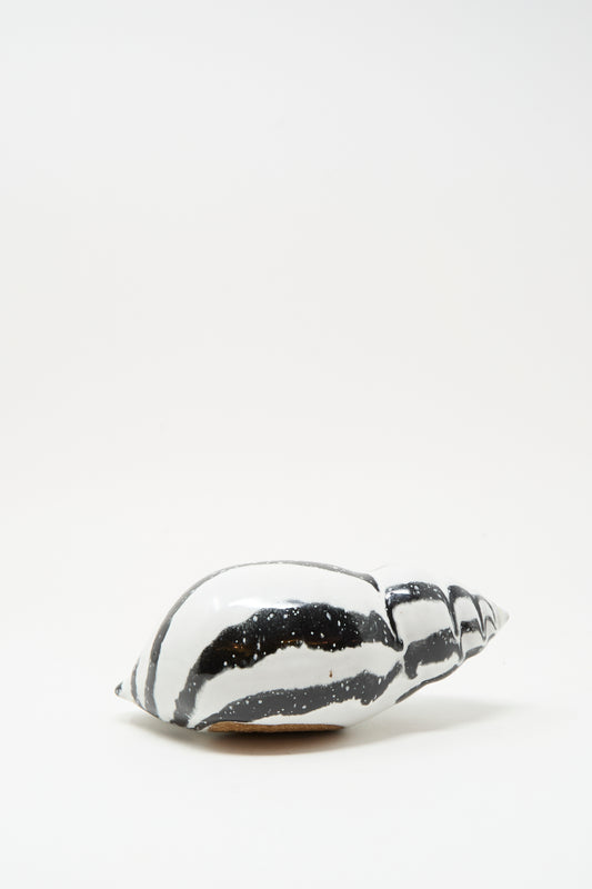The Shell Rattle LXXXV by E.C.C.E, a handmade black and white striped ceramic piece from NYC, rests on a plain white surface.