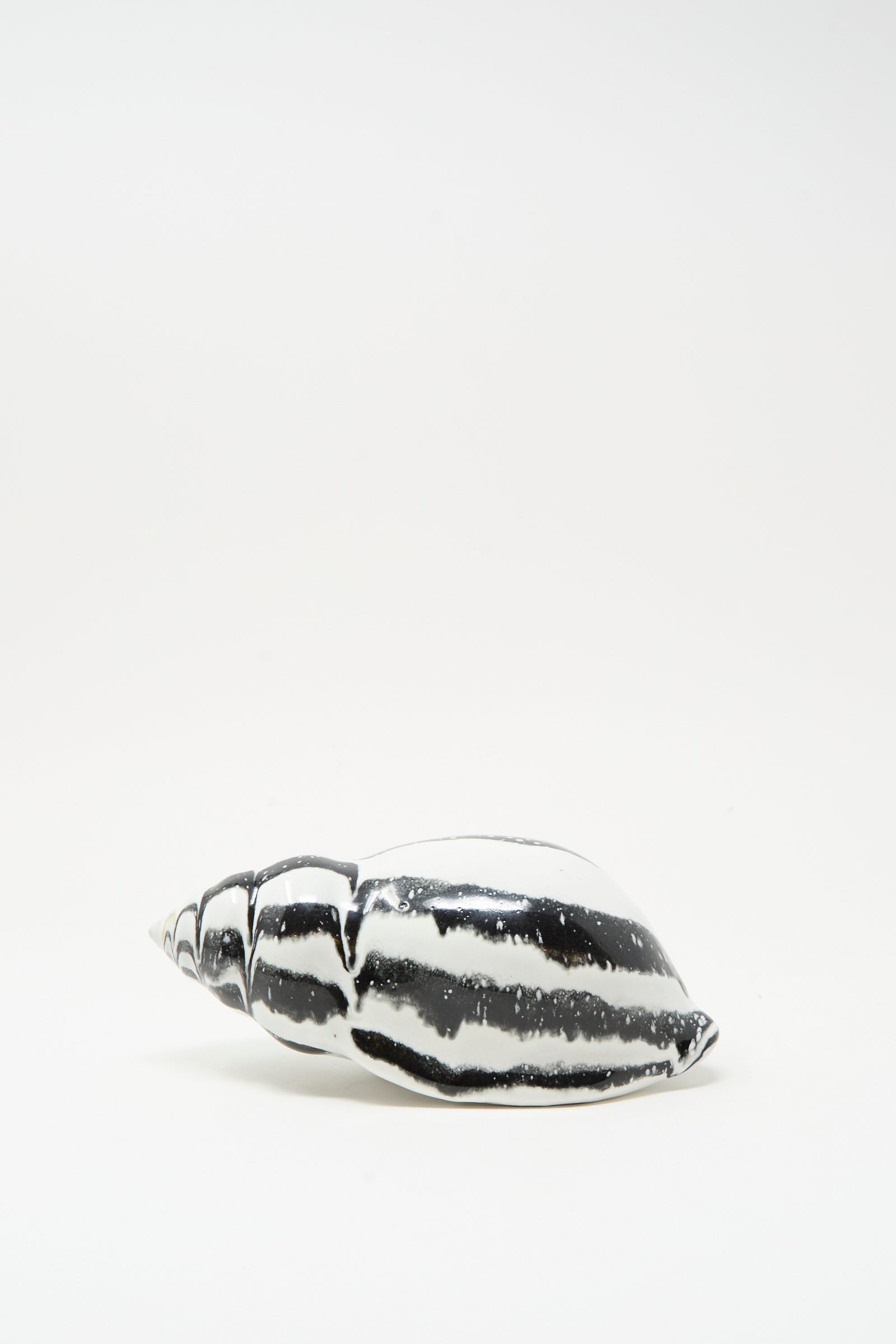 The Shell Rattle LXXXV by E.C.C.E, a handmade black and white striped ceramic piece crafted in NYC, is shown against a plain white background.