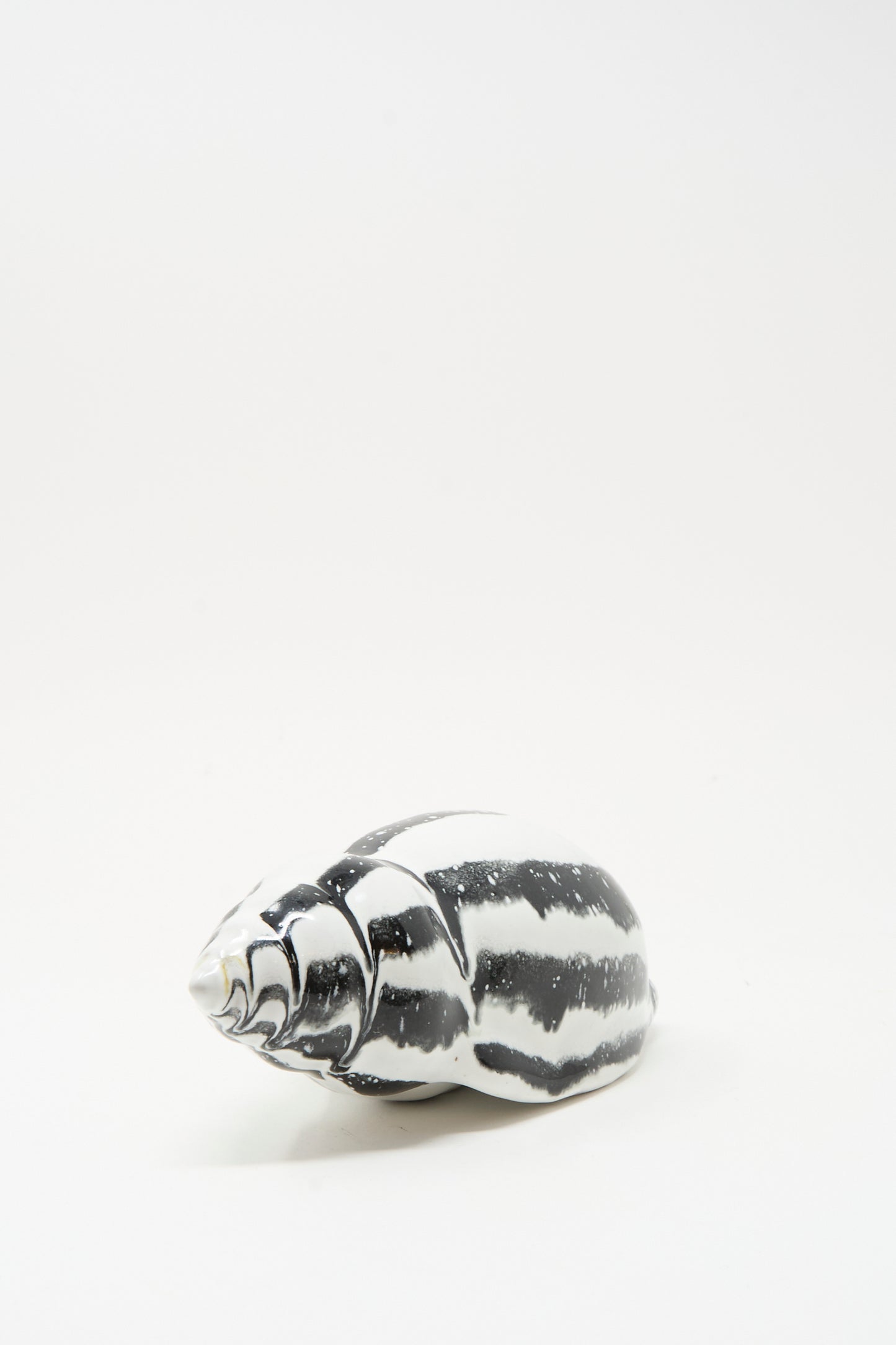 The Shell Rattle LXXXV by E.C.C.E is a handmade black and white striped ceramic piece crafted in NYC, displayed on a plain white background.