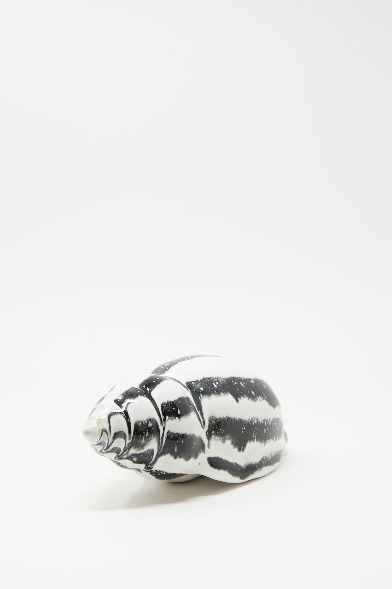 The Shell Rattle LXXXV by E.C.C.E is a handmade black and white striped ceramic piece crafted in NYC, displayed on a plain white background.