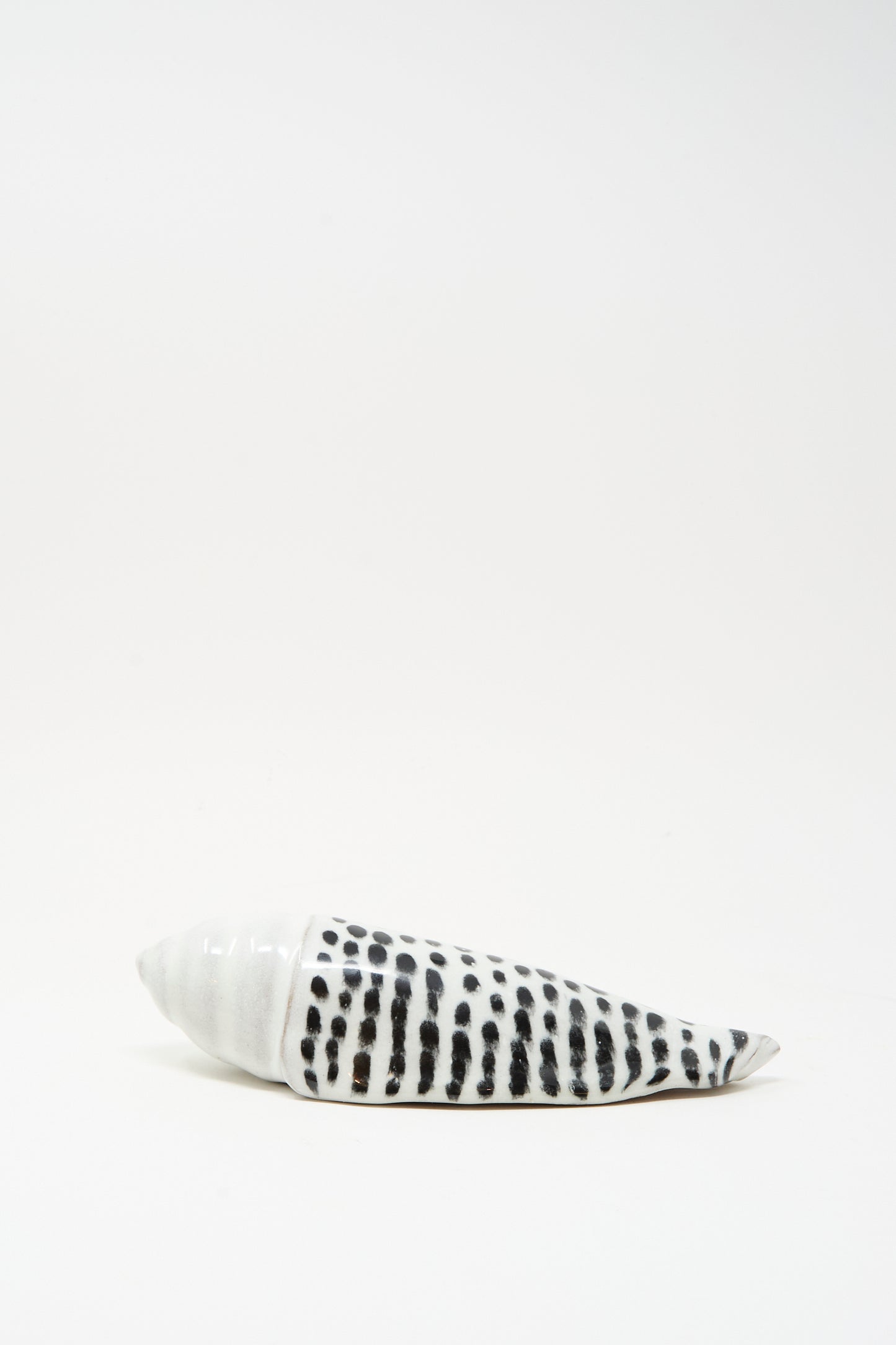 The Shell Rattle XCII by E.C.C.E is a handmade ceramic piece from NYC, featuring black spots and stripes, displayed on a plain white background.