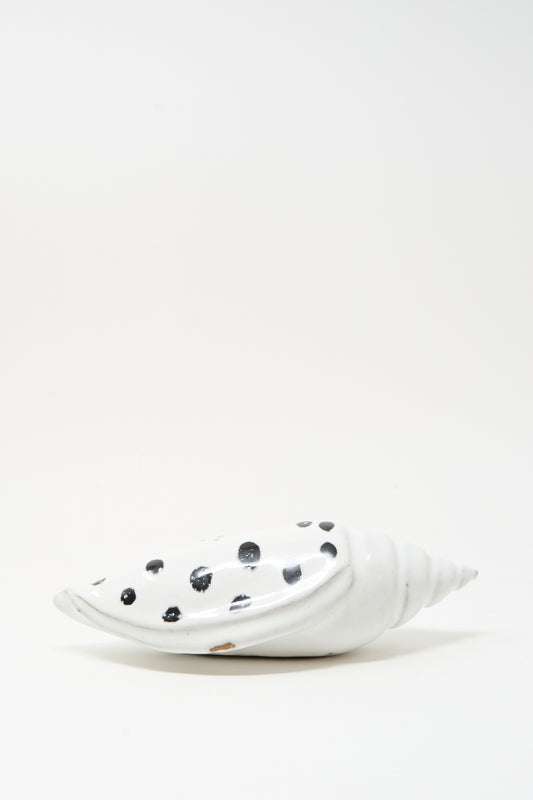 The Shell Rattle XCIII by E.C.C.E is a handmade ceramic shell, white with black spots, displayed on a plain white background.