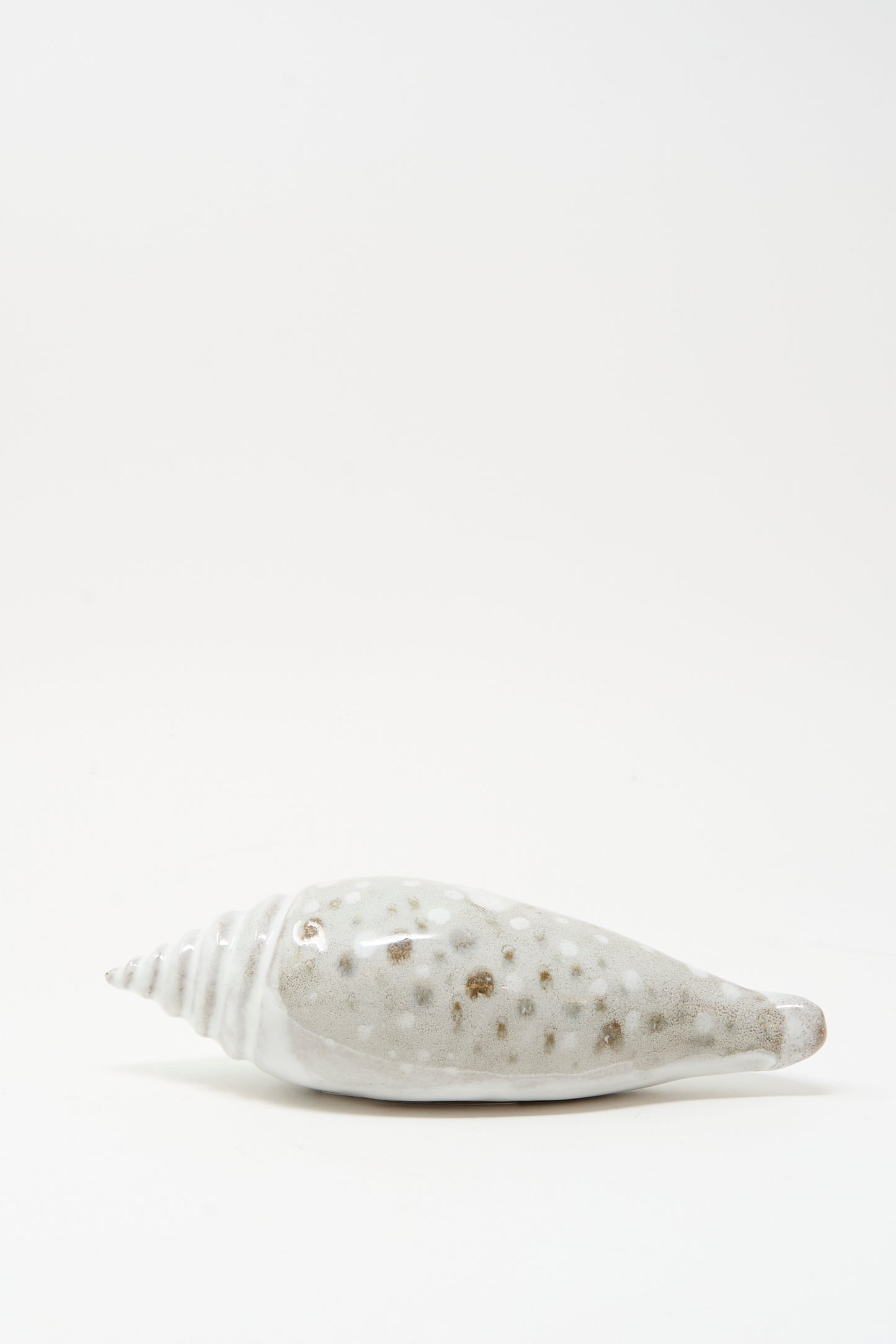 The E.C.C.E Shell Rattle XCV, a handmade white and brown speckled ceramic piece from NYC, rests on a plain white background.
