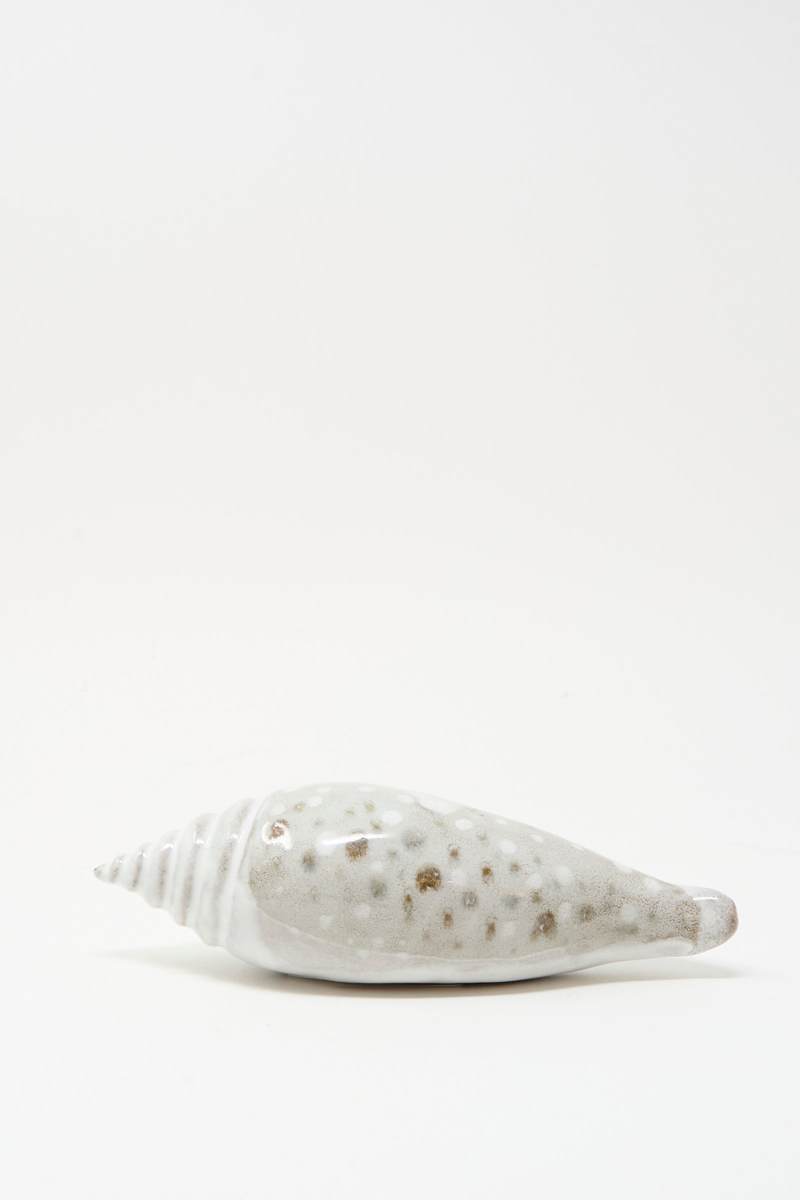 The E.C.C.E Shell Rattle XCV, a handmade white and brown speckled ceramic piece from NYC, rests on a plain white background.
