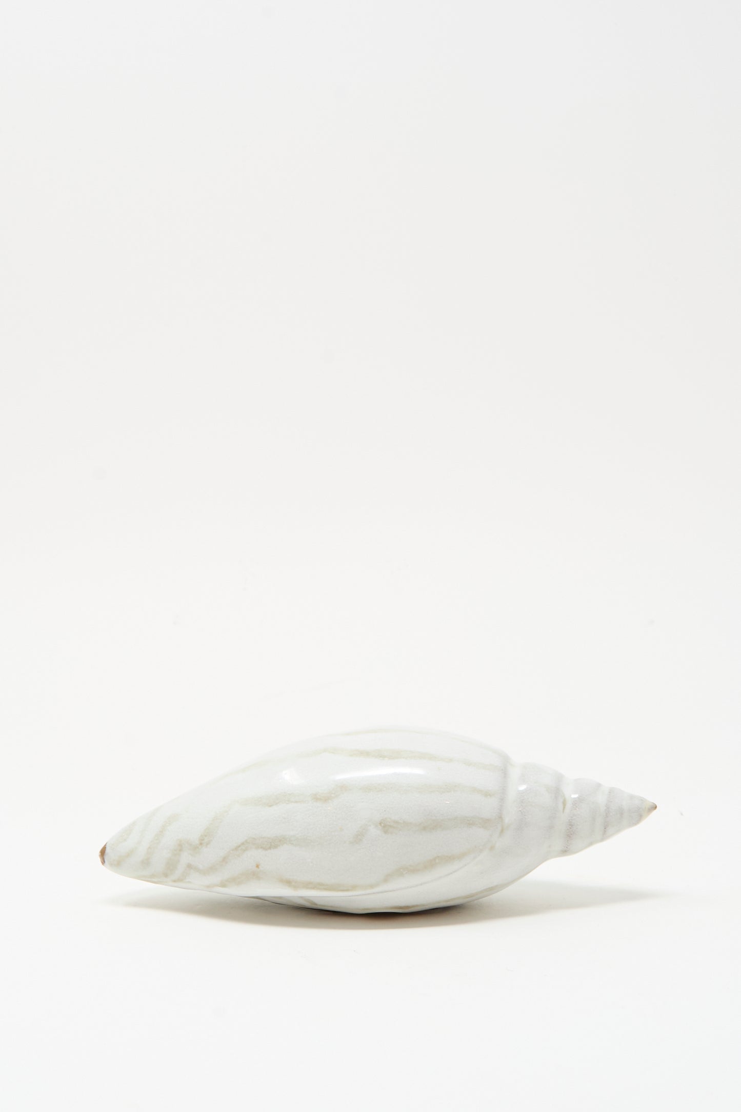 The Shell Rattle LXXVII by E.C.C.E, a handmade ceramic piece with light gray stripes, is displayed on a plain white background.