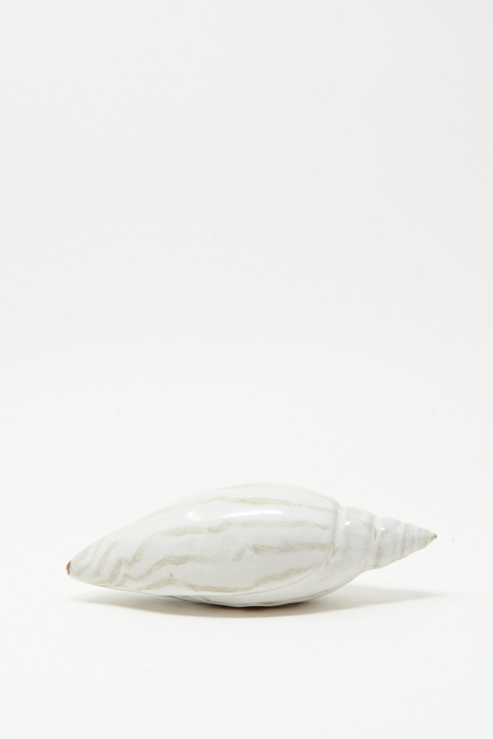 The Shell Rattle LXXVII by E.C.C.E, a handmade ceramic piece with light gray stripes, is displayed on a plain white background.