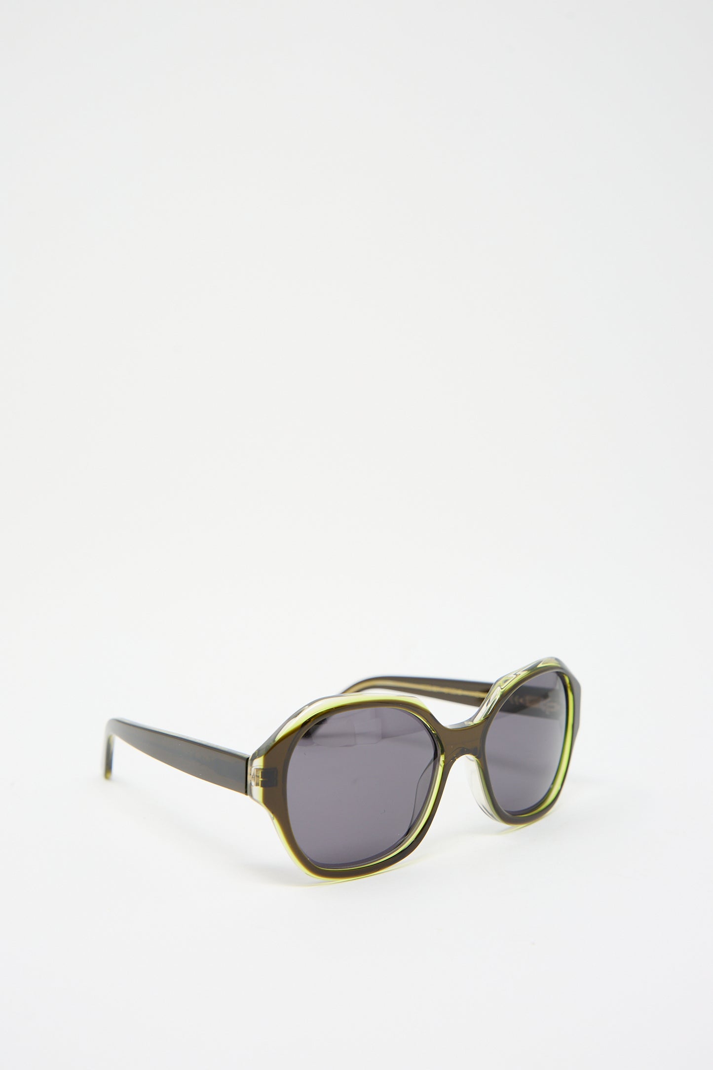 A pair of Eva Masaki 001 Sunglasses in Greens with dark tinted lenses and green accents on the cellulose acetate frame, offering UV protection, displayed against a plain white background.