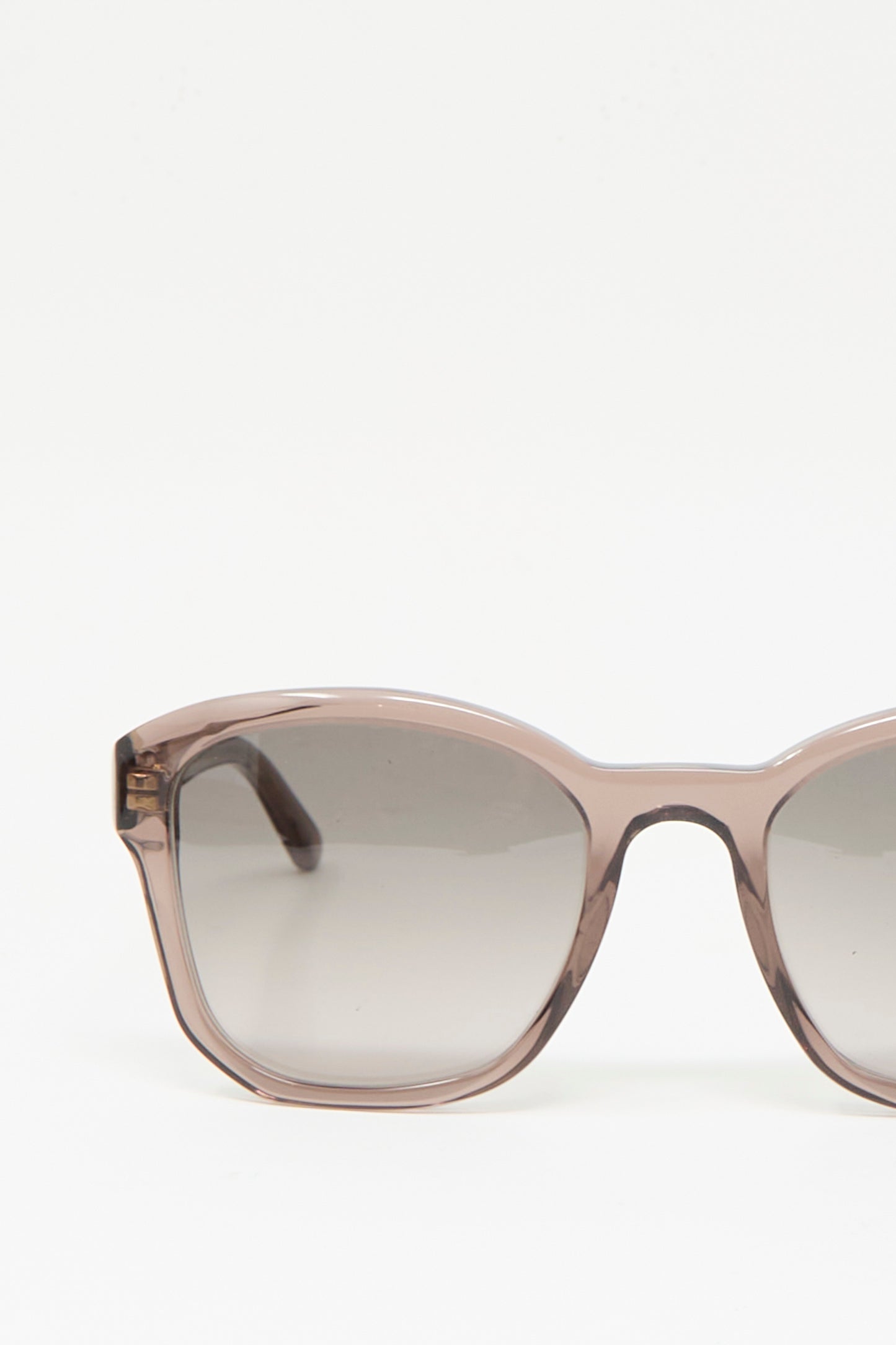 A close-up of the left side of Eva Masaki's BQE Sunglasses in Bambi, handmade in Italy with a transparent frame and brown-tinted lenses, set against a plain white background.