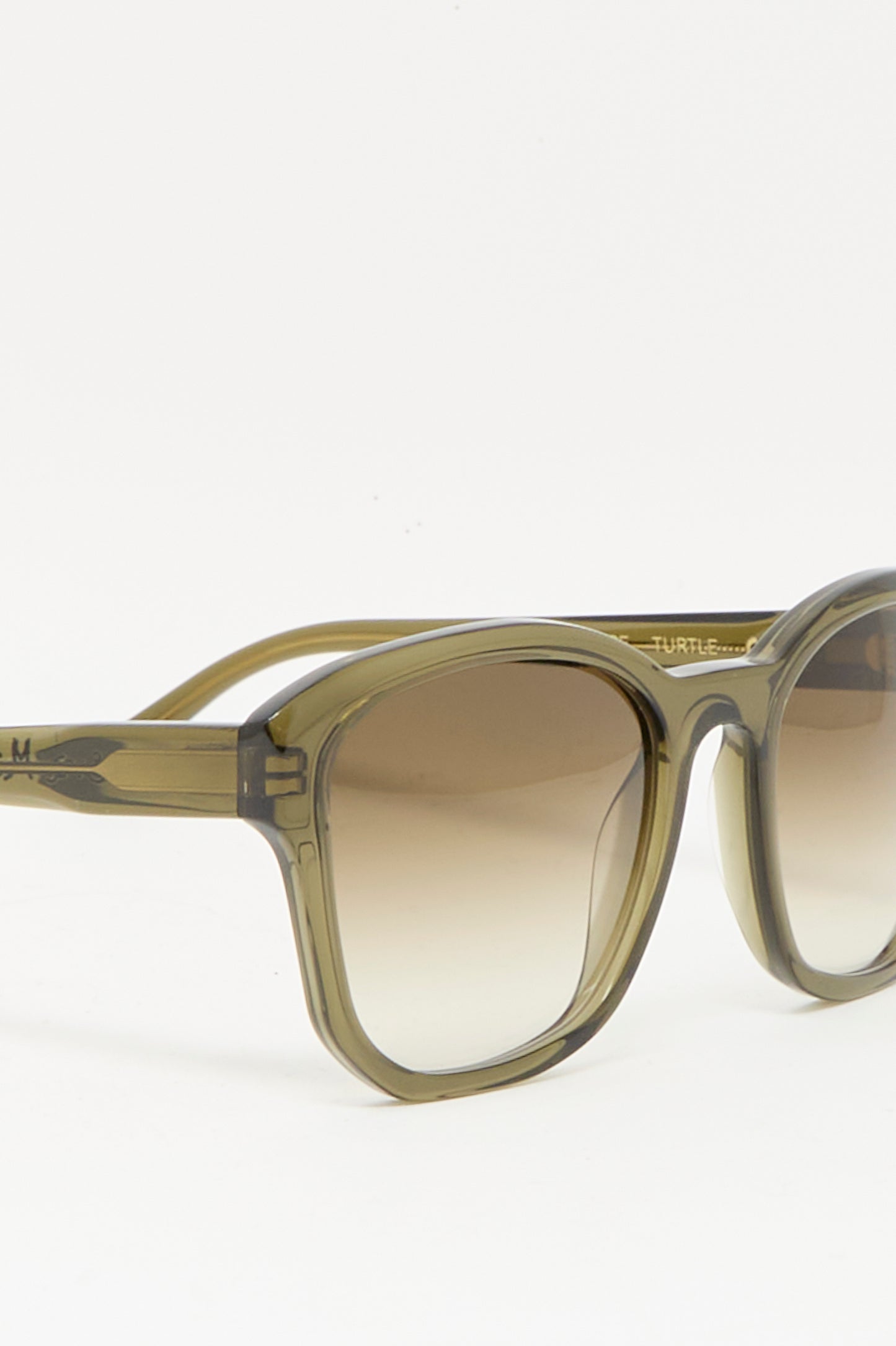 The Eva Masaki BQE Sunglasses in Turtle feature box-shaped Mazzucchelli acetate frames in olive green translucent and gradient brown lenses, shown against a white background.
