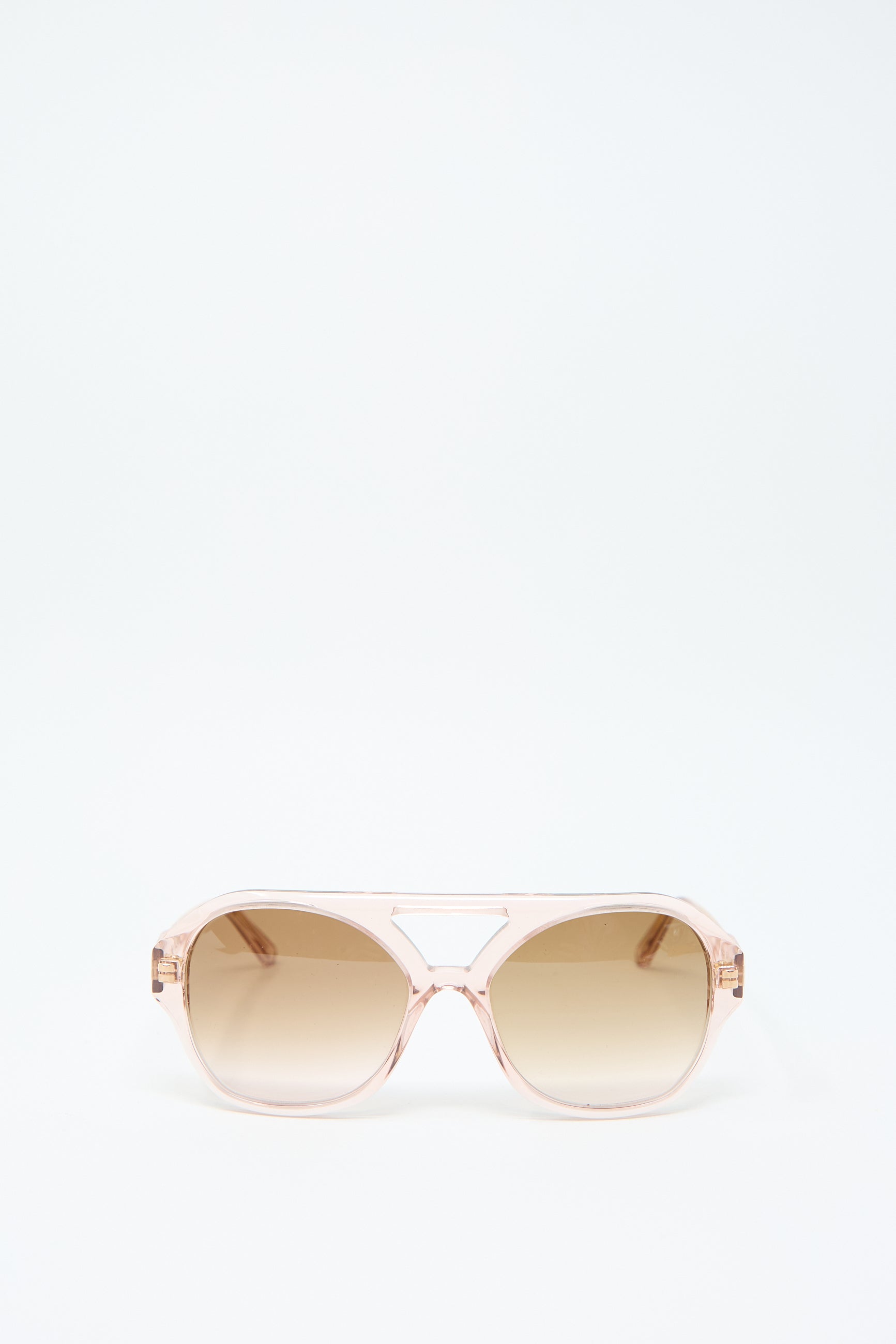 The Chiyo Aviators in Heart by Eva Masaki feature a transparent Italian acetate frame with gradient brown lenses, providing stylish UV protection. These pink sunglasses are beautifully showcased against a plain white background.