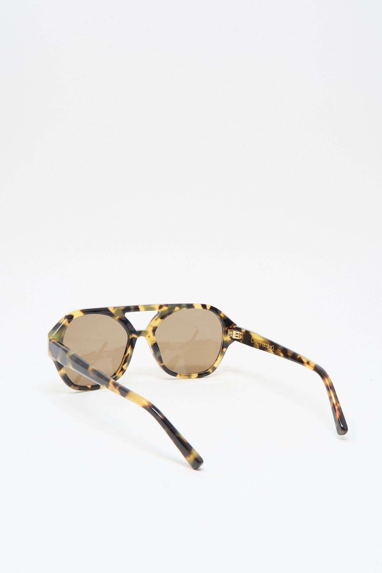 The Chiyo Aviator Sunglasses in Tokyo by Eva Masaki feature Italian tortoiseshell acetate frames, round brown UV-protective lenses, and are shown on a white surface with the arms partially open.