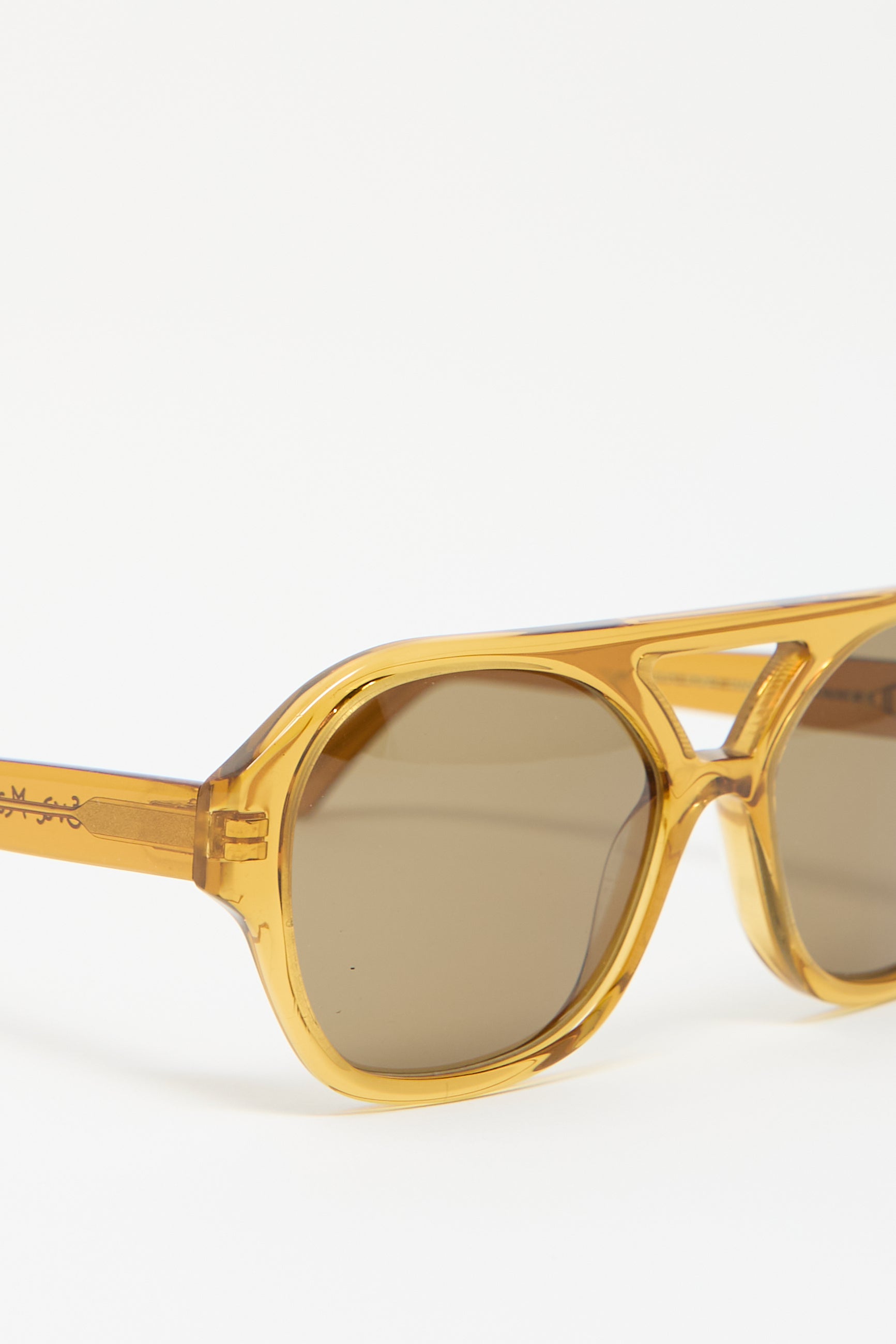 Eva Masaki's Chiyo Aviator Sunglasses in Honey, a pair of amber-colored, plastic-frame sunglasses with UV protection and brown-tinted lenses on a white background.