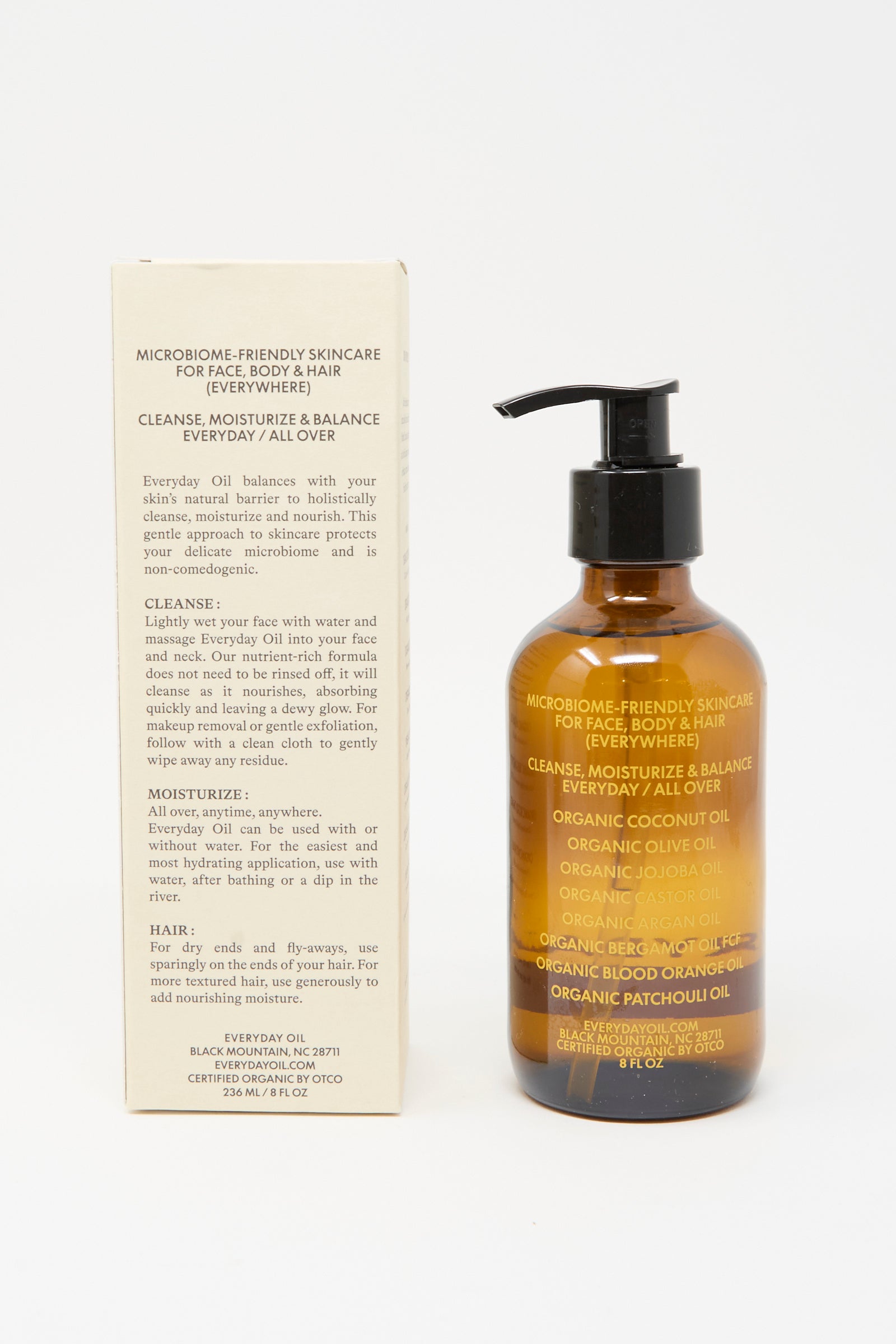 Everyday Oil’s Warm Feelings (8 oz), an all-natural, plant-based moisturizer for face, body, and hair with coconut, jojoba, black cumin, and patchouli oils for microbiome-friendly care, sits in an amber pump bottle beside its box.