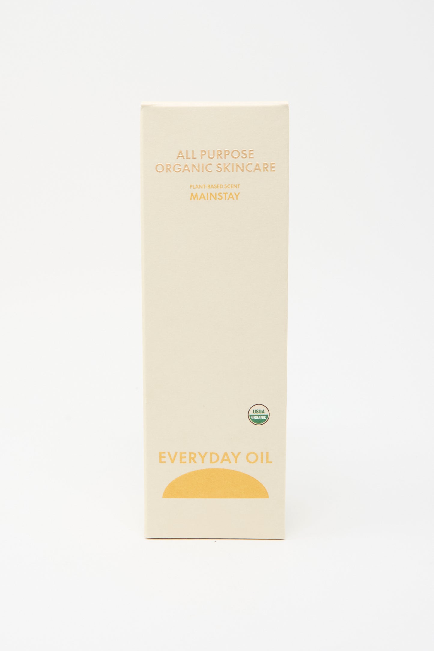 A beige box labeled "Mainstay Blend - 8 Ounces" by Everyday Oil features a yellow semicircle and an organic certification seal on the front—an all-natural skincare essential.