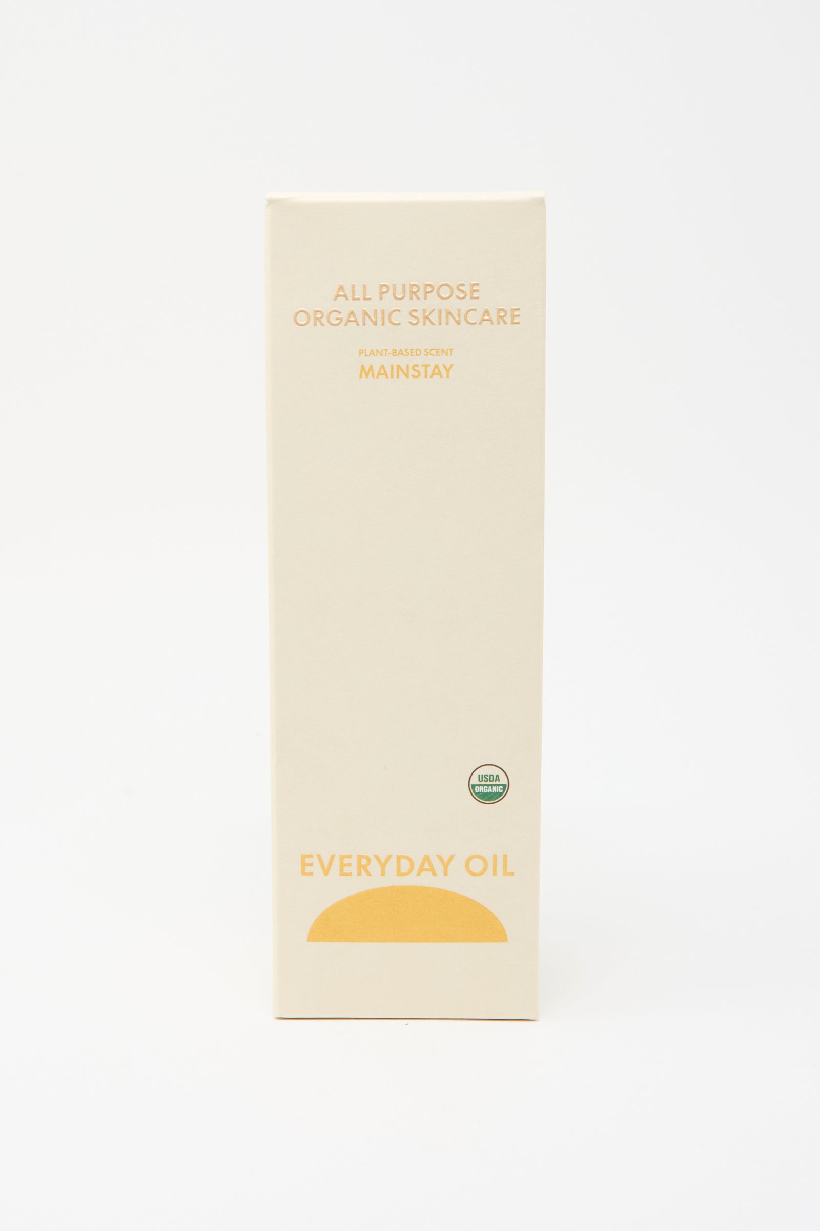 A beige box labeled "Mainstay Blend - 8 Ounces" by Everyday Oil features a yellow semicircle and an organic certification seal on the front—an all-natural skincare essential.