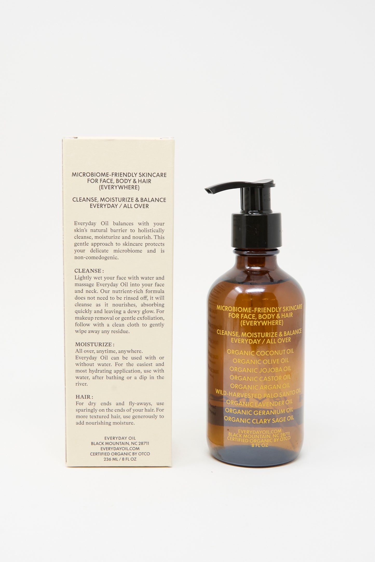 A brown pump bottle of Everyday Oil’s Mainstay Blend (8 oz) stands beside its beige box, both displaying usage and ingredient info for this all-natural cleanser and moisturizer labeled "Microbiome-Friendly Skincare.