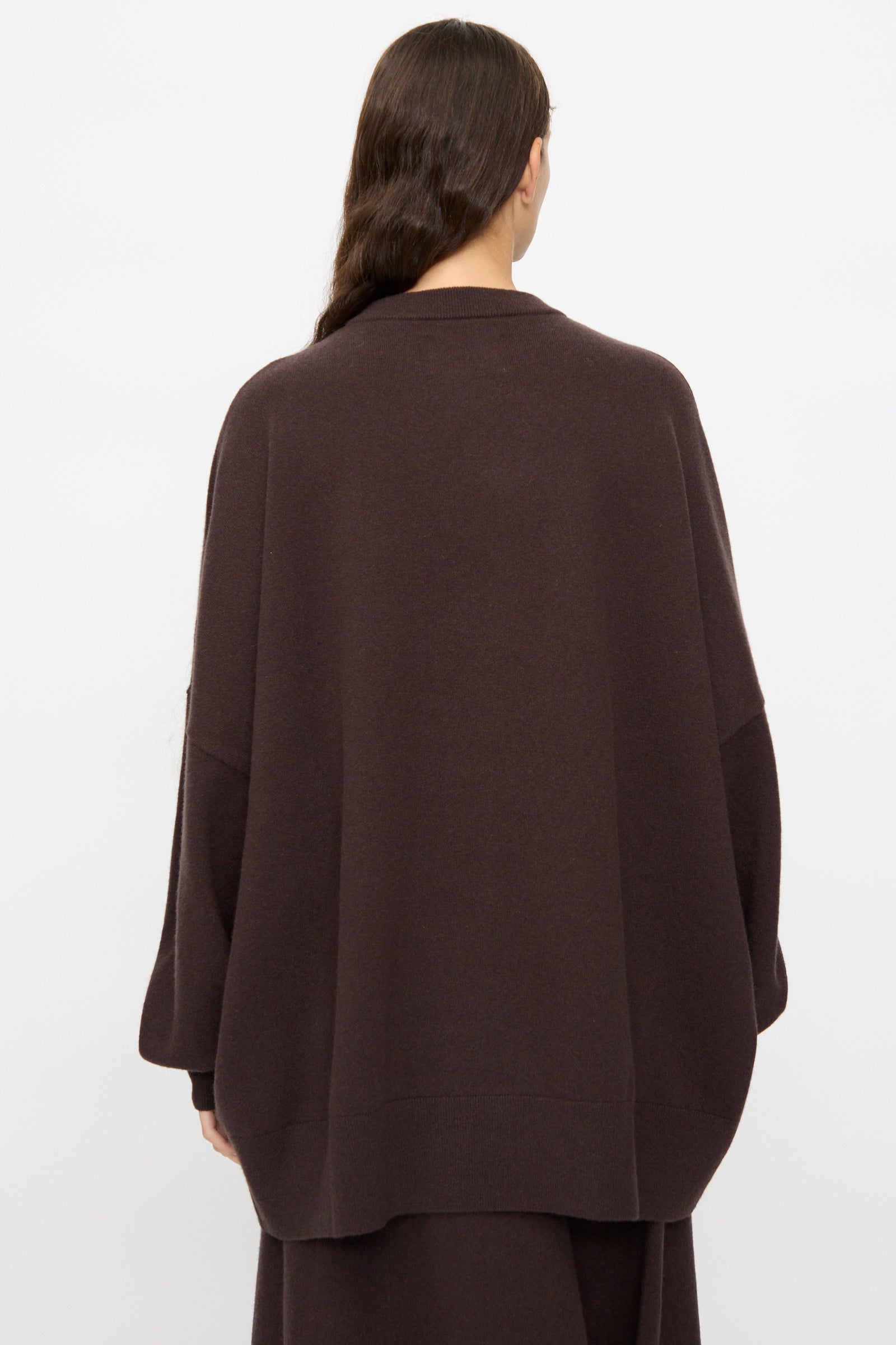 Person with long brown hair, wearing the Extreme Cashmere No. 246 Juna Sweater in Dark Brown, photographed from the back against a plain white background.
