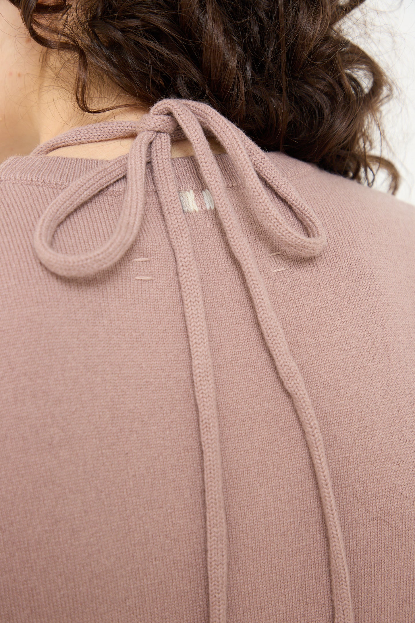 The back of a woman wearing a pink Extreme Cashmere cashmere blend sweater.