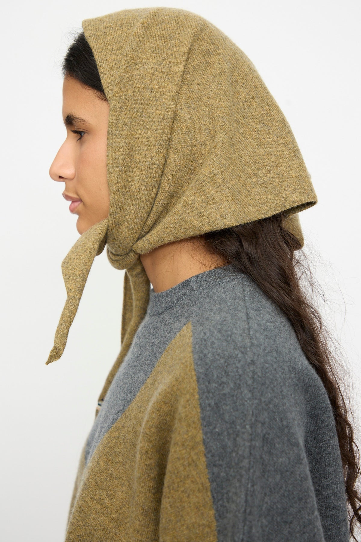 Person in profile wearing the Extreme Cashmere No. 35 Bandana in Hunter and a sweater, standing against a plain white background.