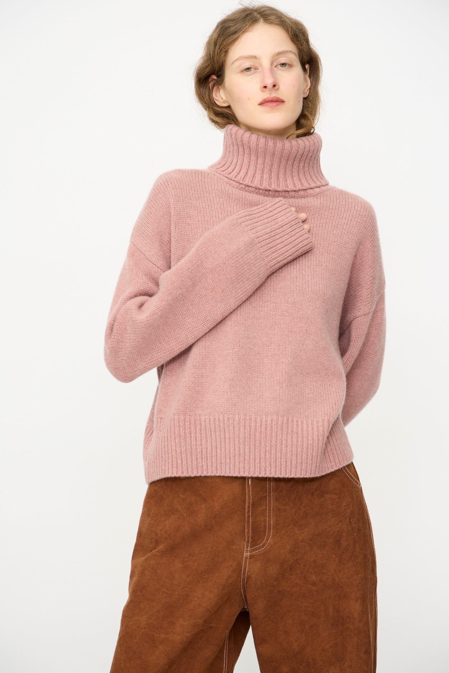 A person wears the Extreme Cashmere No. 434 Crop Xtra Sweater in Moor and brown wide-leg pants, standing against a plain light background.