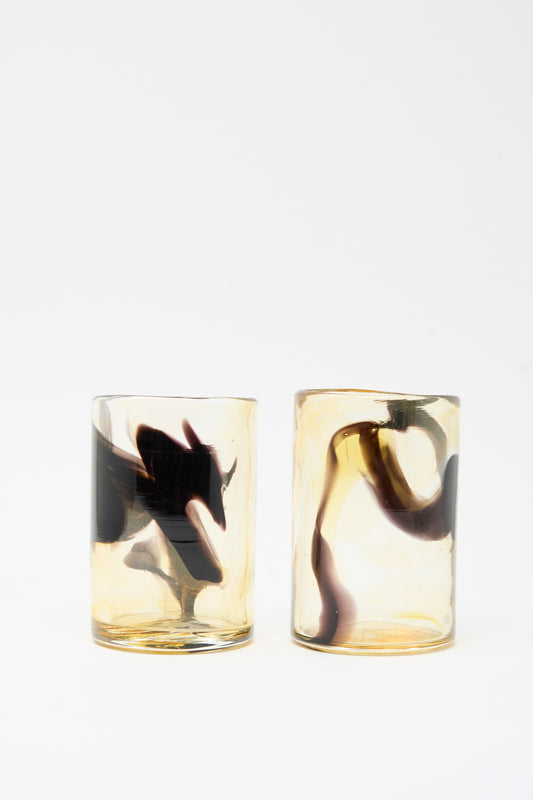 Two Hand Dyed Fumé glass tumblers featuring amber-toned glass with swirling black smoke-like patterns.