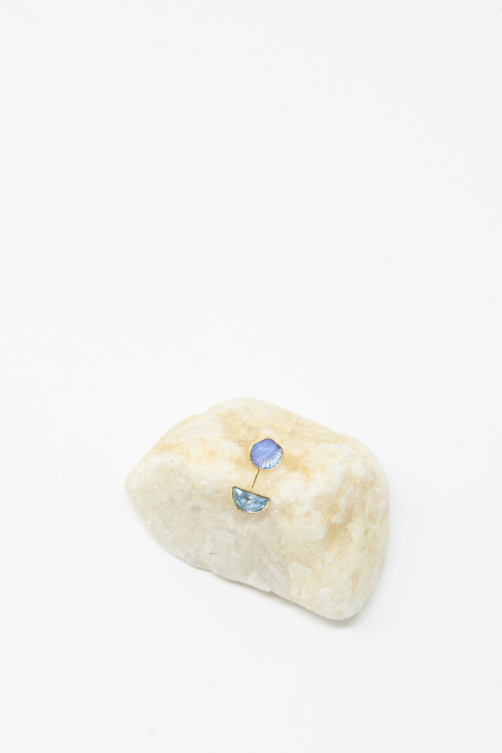 The Detachable Drop Earring in Blue Shell by Grainne Morton is an 18K gold plated handmade stud with a blue shell shape and semi-circle dangle, shown on beige stone against a white background.