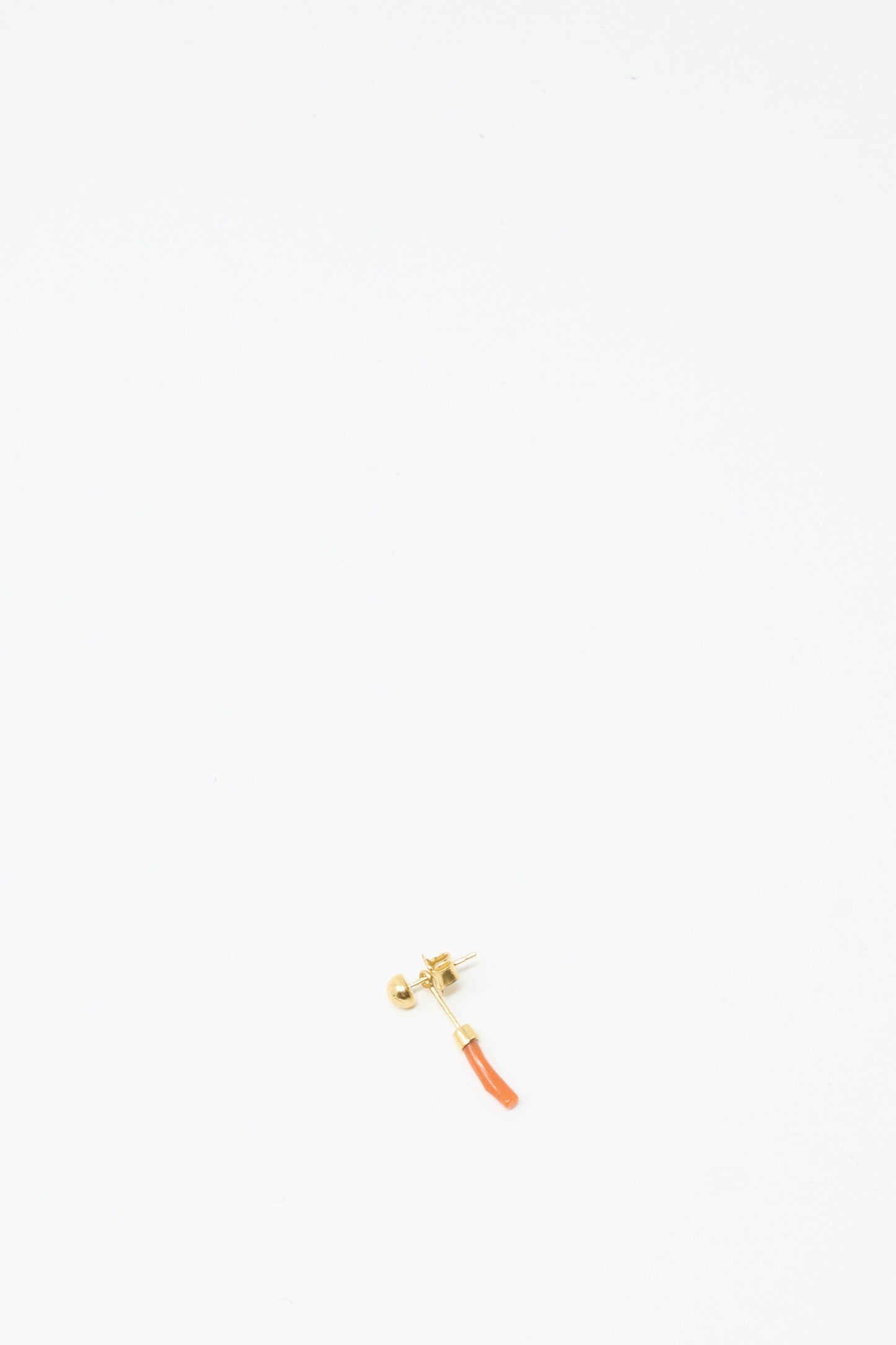 The Grainne Morton Detachable Drop Earring in Coral is a single 18K gold plated earring, handmade in Edinburgh, featuring a small curved orange pendant, shown against a plain white background.