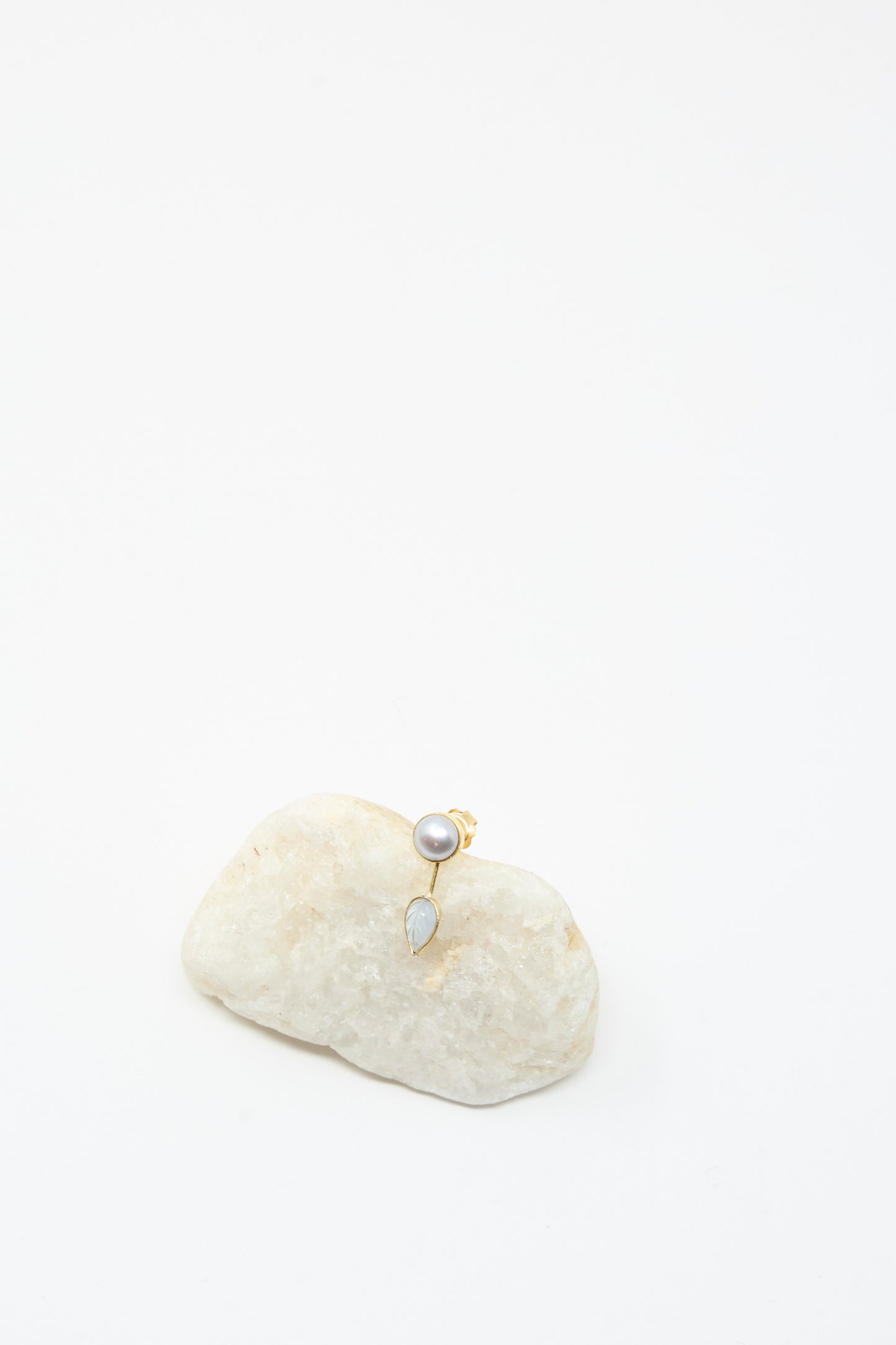 The Detachable Drop Earring in Pearl and Leaf by Grainne Morton features a gold pearl stud with a drop-shaped gemstone, beautifully handmade in 18K gold plated silver, displayed on a white stone against a plain background.