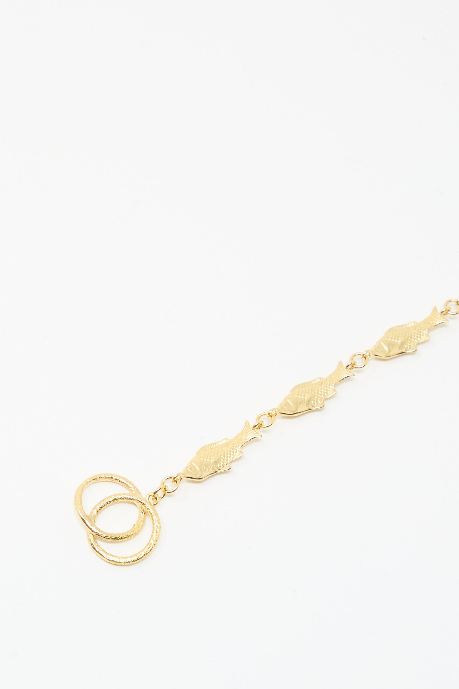 The Grainne Morton Fish Bracelet is handmade in Edinburgh from gold-plated silver, featuring linked fish-shaped charms and two interlocking rings, beautifully displayed on a white background.