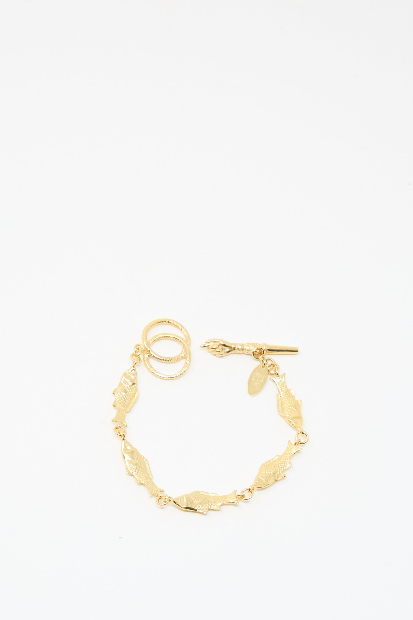The Fish Bracelet by Grainne Morton is a gold-plated silver piece with leaf-shaped links and a toggle clasp, handmade in Edinburgh, shown against a plain white background.