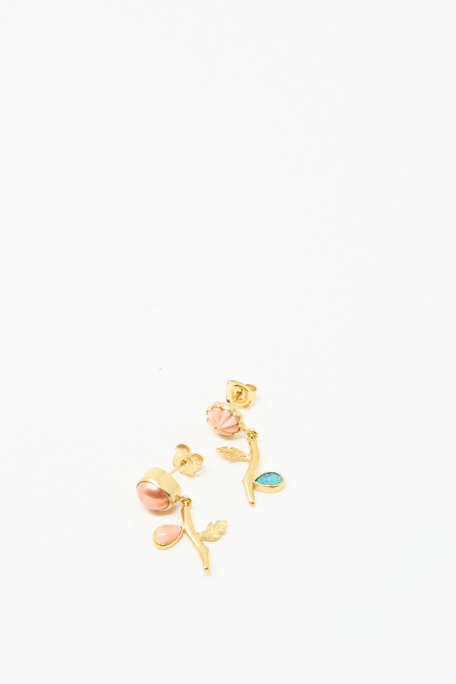 Grainne Morton's Flower Drop Earrings feature pink and blue stones on a white base, featuring leaf and branch designs for a mismatched look with ethically sourced materials, viewed against a white backdrop. 