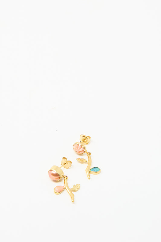 Grainne Morton's Flower Drop Earrings feature pink and blue stones on a white base, featuring leaf and branch designs for a mismatched look with ethically sourced materials, viewed against a white backdrop. 